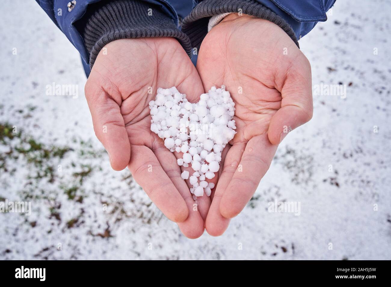 Detailansicht von Menschenhänden halten Schnee in Form von Herzen in den Handflächen. Wntertime Freizeitaktivität Konzept Stockfoto