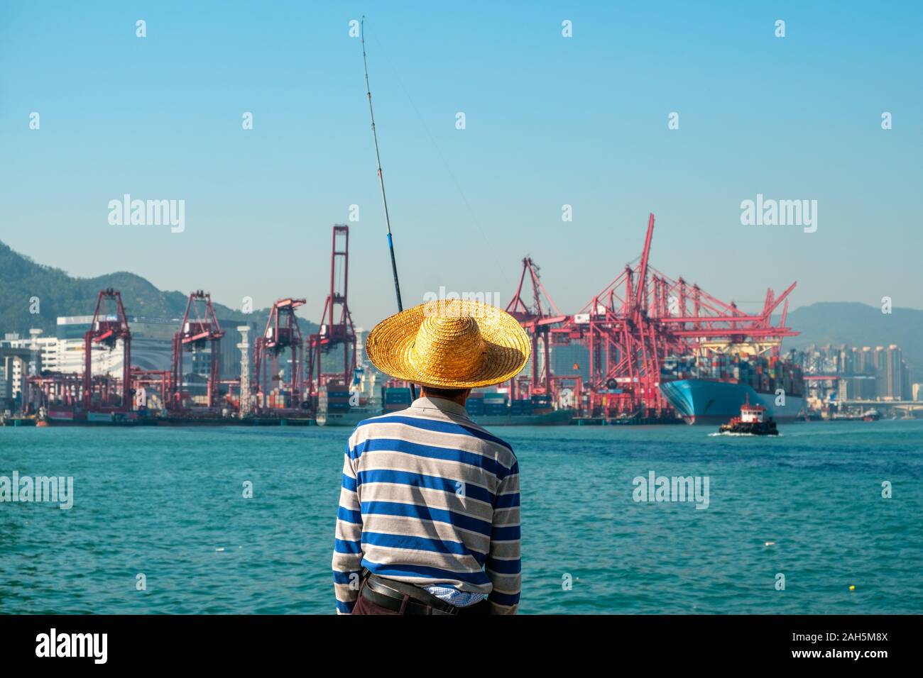 Fisher Mann mit Angelrute von hinten in der Nähe der Container schiff und Fracht Hafen in HongKong Stockfoto