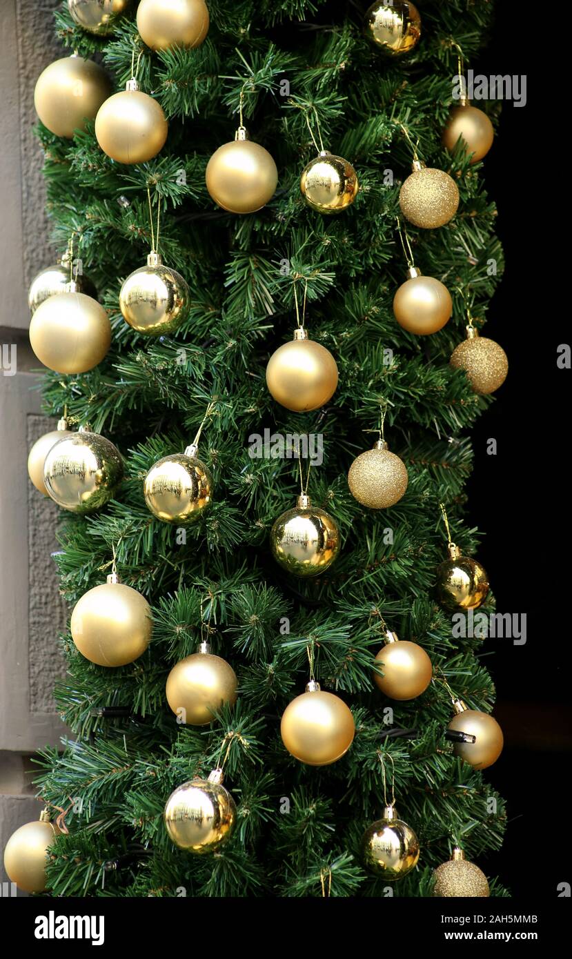 Traditionell dekorierte Christbaumkugeln auf Kranz aus Tannenzweigen und grün leuchtende Girlande. Zweige Kiefer, Gold und Silber Weihnachtskugeln. Stockfoto