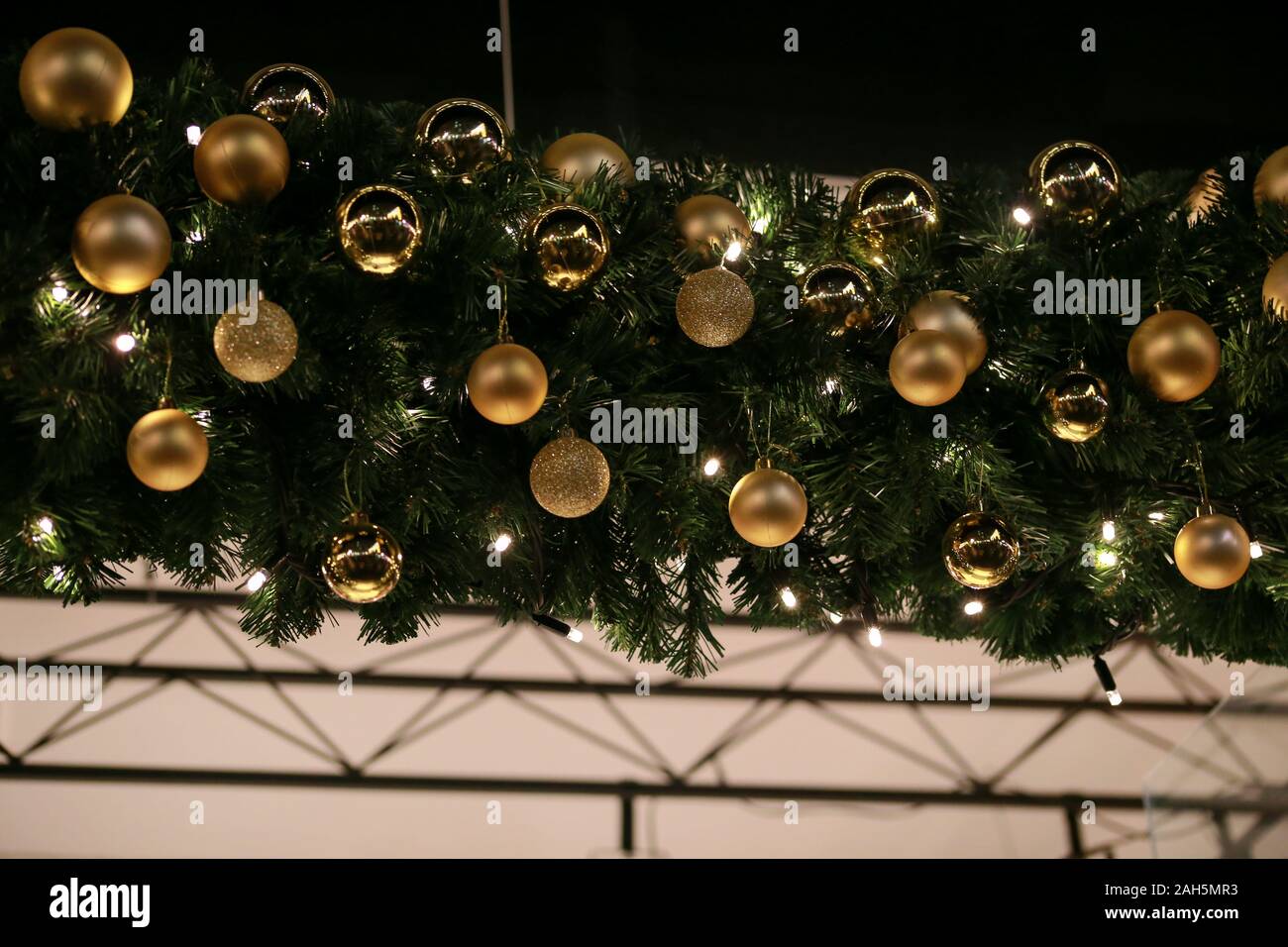 Traditionell dekorierte Christbaumkugeln auf Kranz aus Tannenzweigen und grün leuchtende Girlande. Zweige Kiefer, Gold und Silber Weihnachtskugeln. Stockfoto