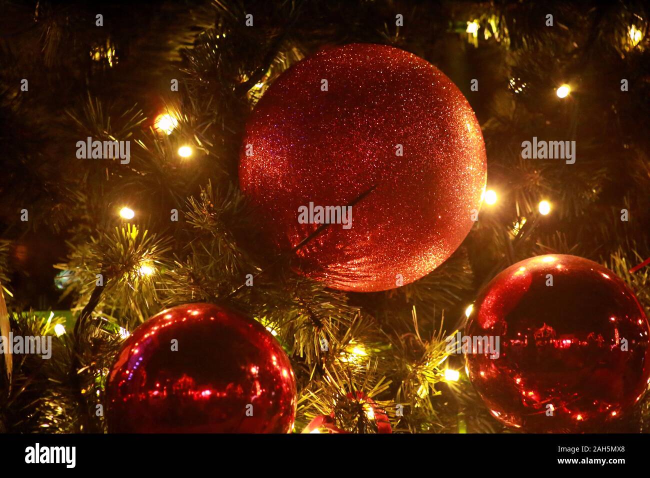 Traditionell dekorierte Christbaumkugeln hängt an grüne Zweige Baum der Kiefer. Leuchtend rote Kugeln am Weihnachtsbaum Tanne oder mit string Reis Glühlampen Fichte. Stockfoto