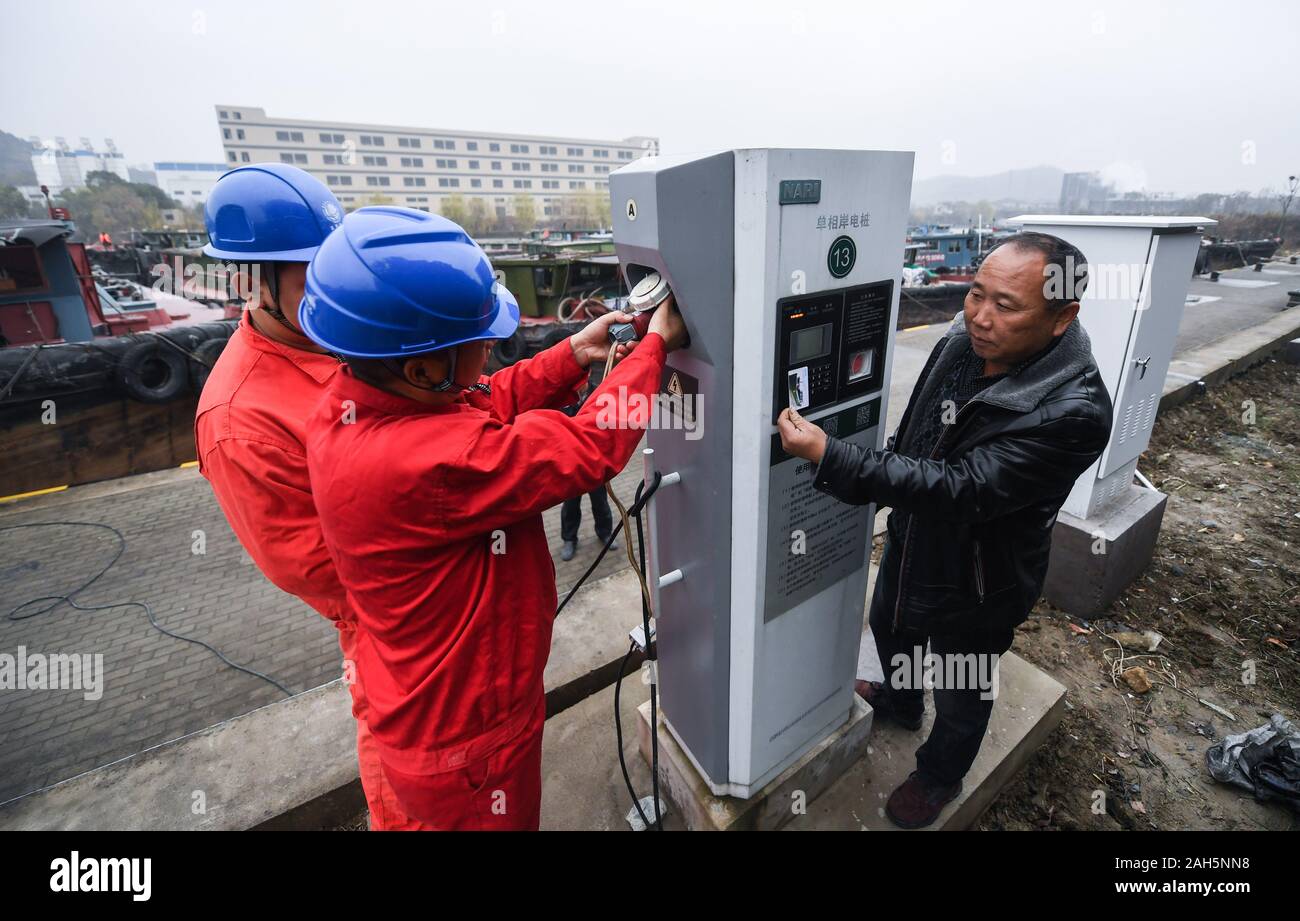 Changxing, der chinesischen Provinz Zhejiang. 25 Dez, 2019. Menschen arbeiten an einer Ladestation Haufen die sichere Verwendung von Strom für Schiffe, die im Winter bei Lyushan Stadt Changxing County, im Osten der chinesischen Provinz Zhejiang, Dez. 25, 2019 zu garantieren. Changxing Grafschaft hat in den letzten Jahren wurde die Förderung der Nutzung von Elektrizität Abgas- und Lärmemissionen zu reduzieren. Credit: Xu Yu/Xinhua/Alamy leben Nachrichten Stockfoto