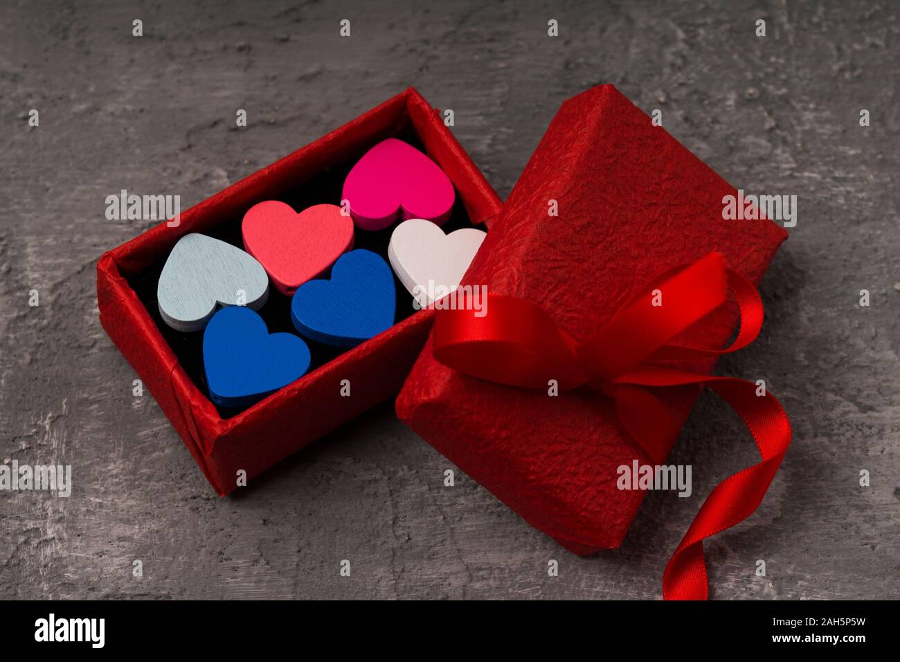 Valentines Tag Hintergrund mit Herzen und roter Geschenkbox auf konkrete Brett. Bis schließen Stockfoto