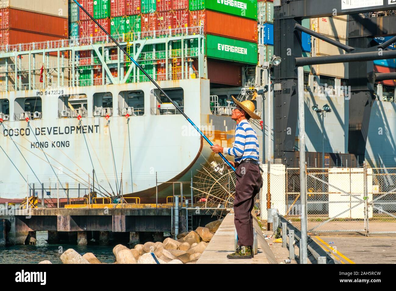 Fisher Mann mit Angelrute von hinten in der Nähe der Container schiff und Fracht Hafen in HongKong Stockfoto