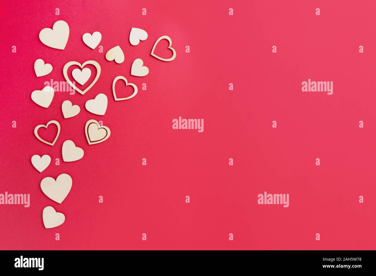 Holz- Herzen auf dem hellen roten Hintergrund. Zusammenfassung Hintergrund mit hölzernen Formen. Valentinstag, Muttertag, Geburtstag Grußkarten, Einladung, Stockfoto