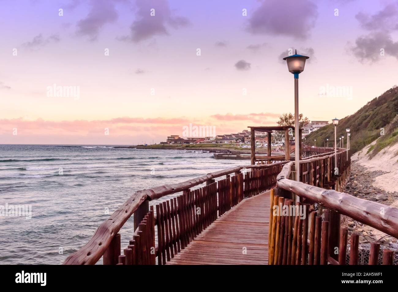 Boardwalk führt vorbei an Strand und Meer in Gonubie iin East London, Südafrika in den Sonnenuntergang am Abend Stockfoto