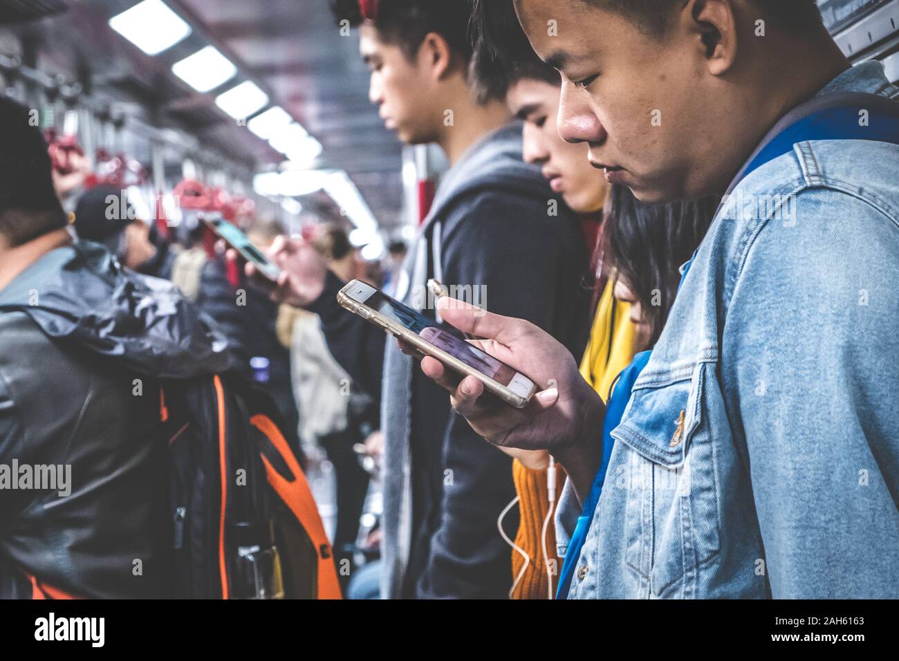 HongKong, China - November, 2019: Leute, die auf der Suche am Handy innerhalb der MTR-Bahnhof/U-Bahn in HongKong Stockfoto