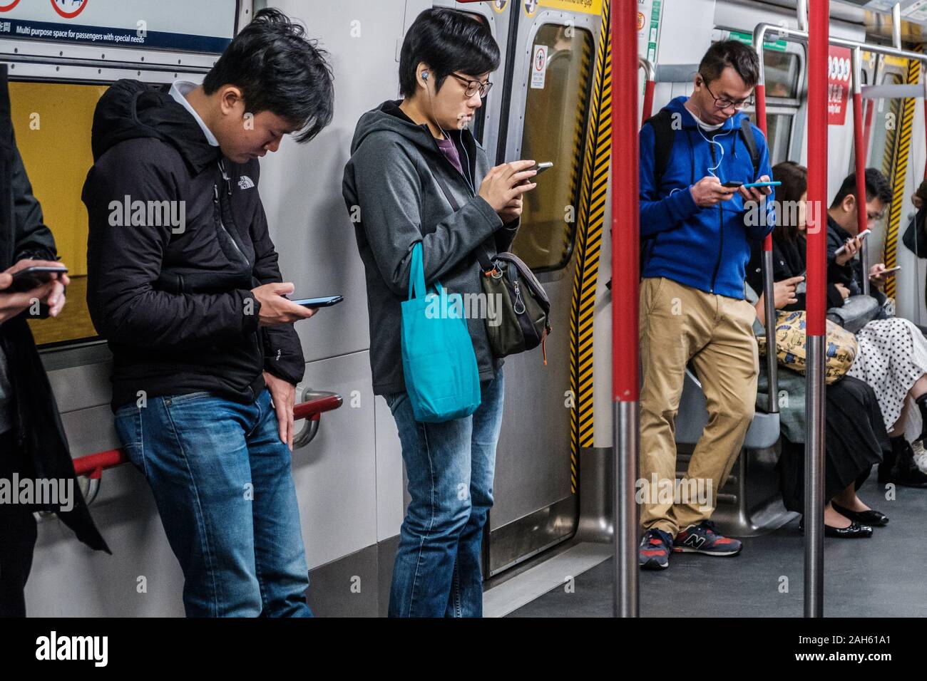 HongKong, China - November, 2019: Leute, die auf der Suche am Handy innerhalb der MTR-Bahnhof/U-Bahn in HongKong Stockfoto