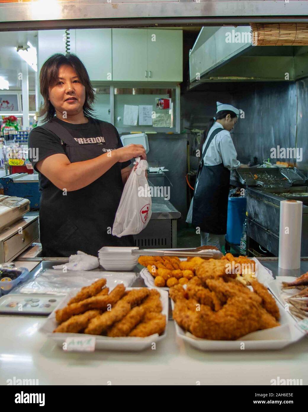 Naha, Okinawa, Ryukyu Inseln. 1. November 2006. Ein Okinawan Frau an ihrem Essen stand in der Mutsumibashi Einkaufspassage in Naha ein beliebtes Ziel der Touristen. Naha, die Hauptstadt der Präfektur Okinawa, die Inselgruppe südlich von Japan auf dem Festland, ist das politische und wirtschaftliche Zentrum von Okinawa, von Tourismus, Handel und Dienstleistungssektor dominiert. Credit: Arnold Drapkin/ZUMA Draht/Alamy leben Nachrichten Stockfoto