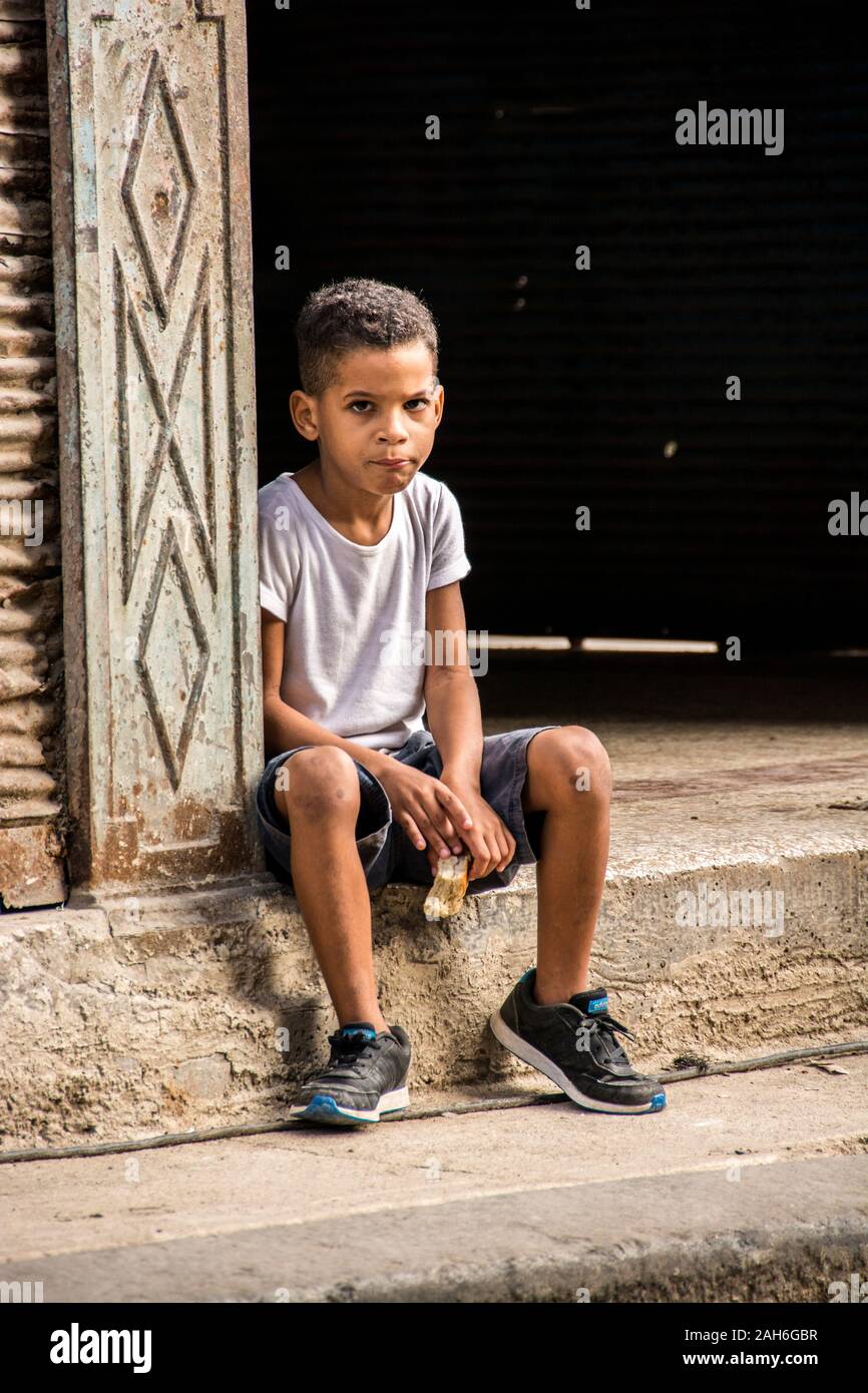 Bürger von Havanna Serie - ein einsamer, kubanischen Jungen selbst sitzen auf dem Stoop seiner Wohnung. Stockfoto