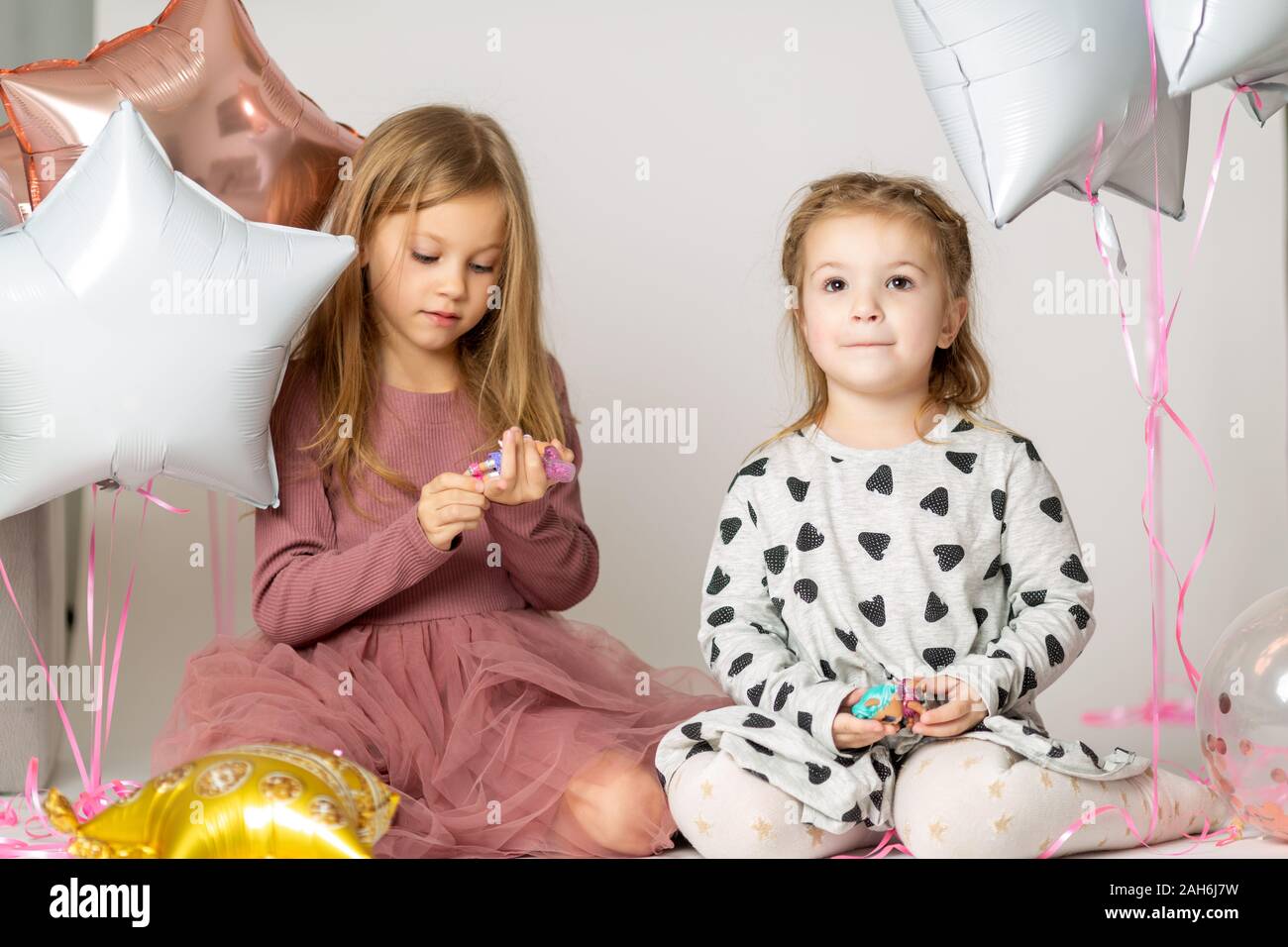Zwei blonde kleinen Schwestern Spielen sitzen auf dem Boden in einem Photo Studio Stockfoto