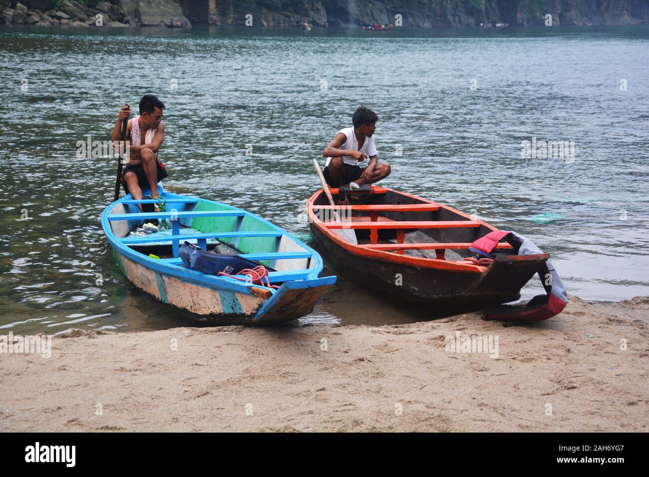 Nahaufnahme von zwei hölzernen blaue und rote Farbe Boote und Bootsmann sitzen, im Fluss der Umngot Dawki, Shillong, Meghalaya, selektive Fokussierung Stockfoto