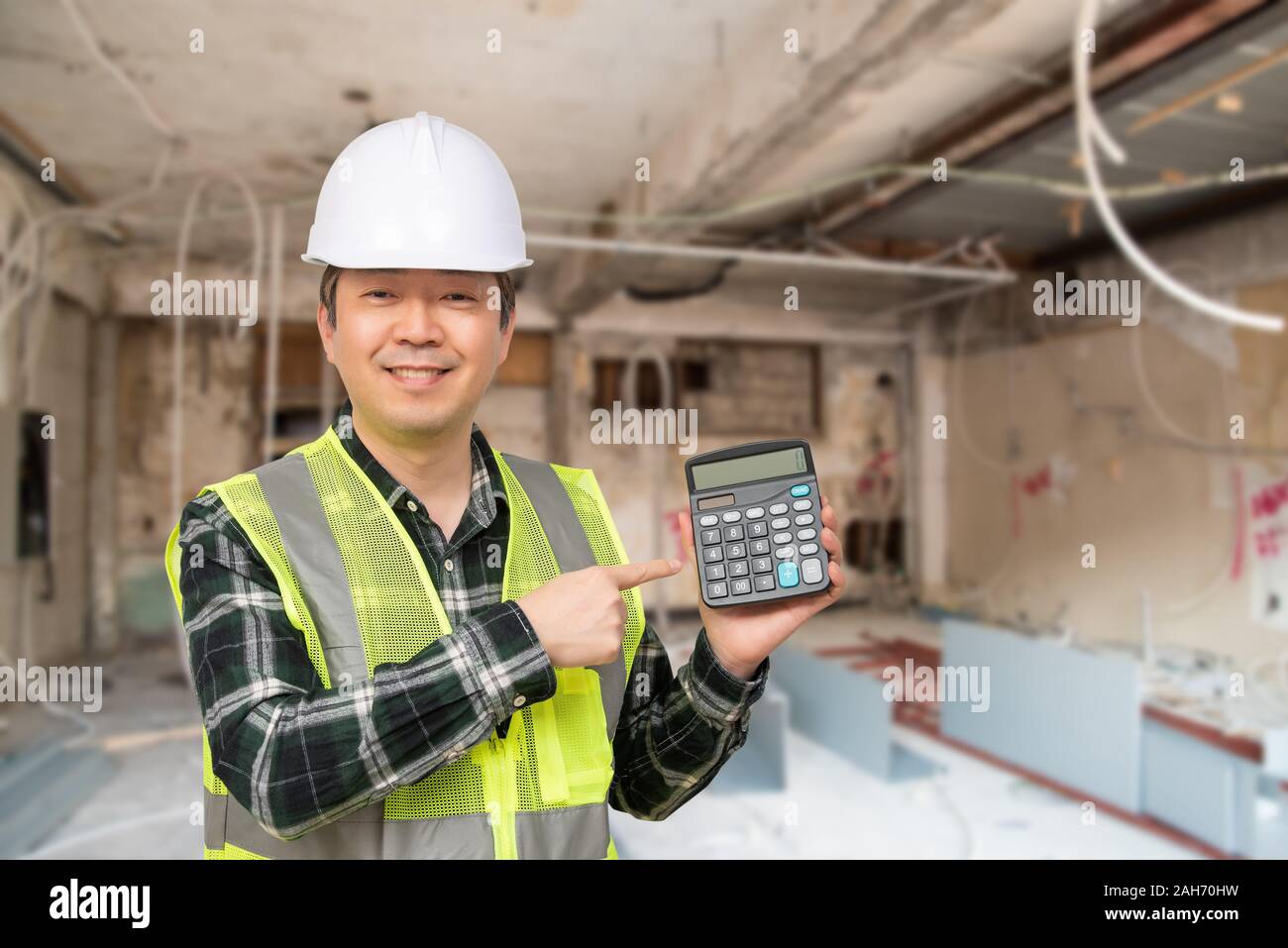 Ein im mittleren Alter asiatischer Mann Tragen eines weißen Arbeit Gap und Arbeit Anzug Holding einen Taschenrechner in der Hand. Stockfoto
