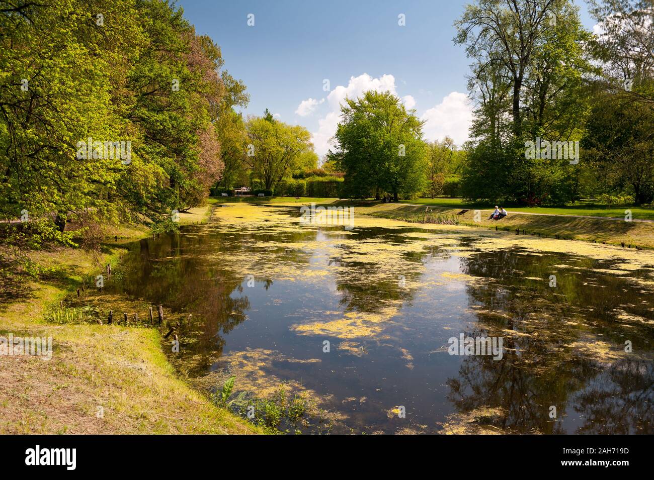 Leute, die durch den Garten Teich in Nieborów Park im Frühling sitzen, Blick auf den Garten in Polen, Europa, Touristen, Freizeit in der Natur. Stockfoto