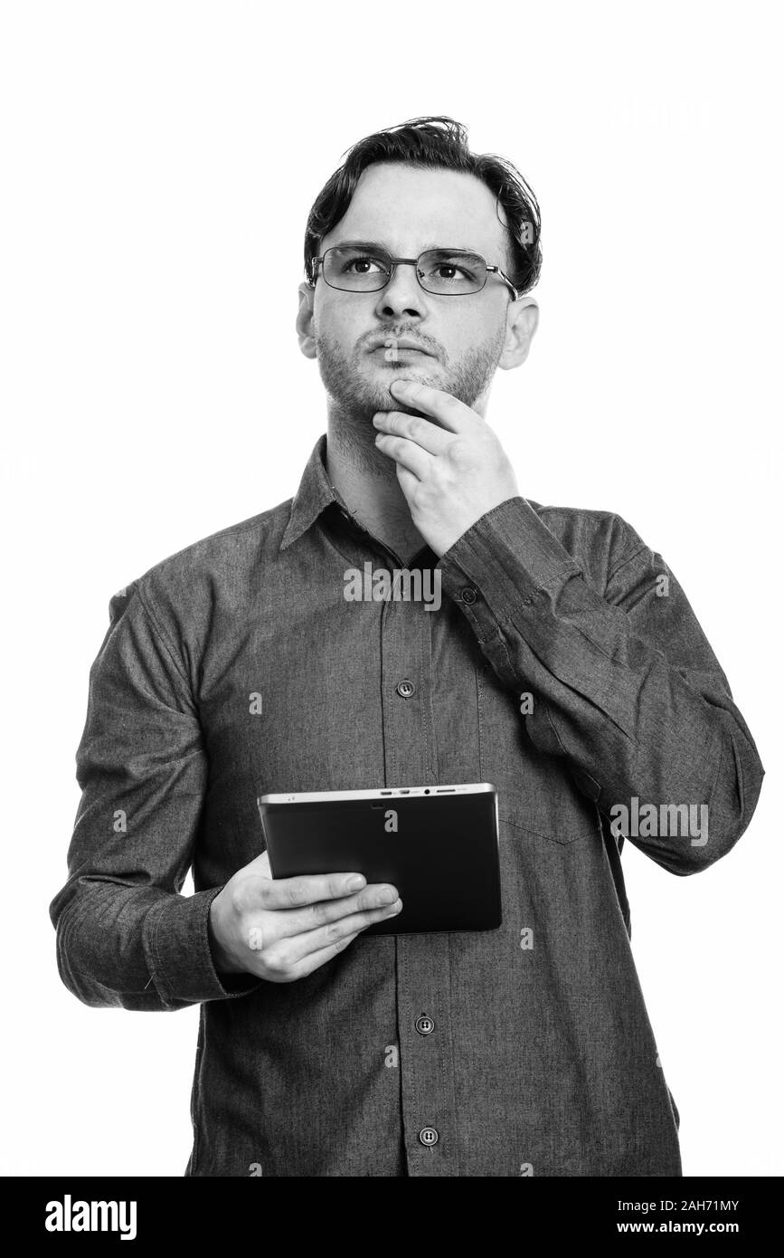 Studio shot der formalen jungen Mann mit digitalen Tablet beim Denken und Suchen Stockfoto