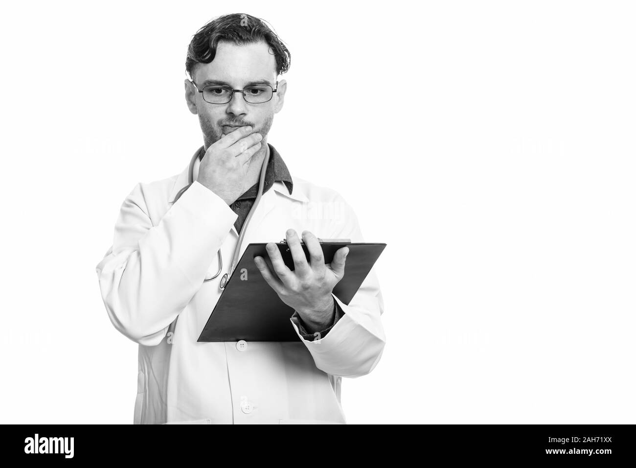 Studio erschossen der junge Mann Arzt holding Zwischenablage beim Denken Stockfoto