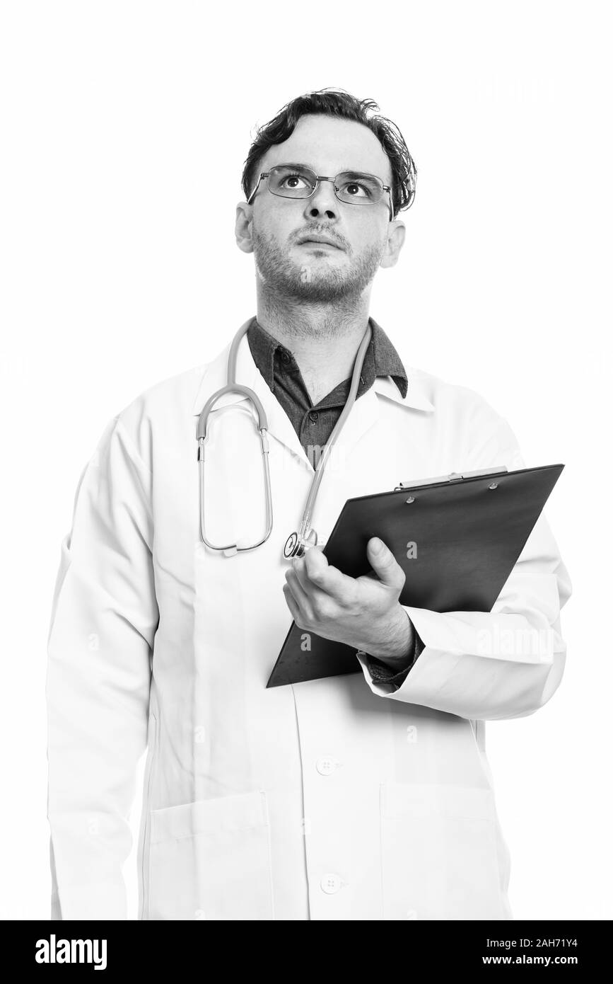 Studio erschossen der junge Mann Arzt holding Zwischenablage beim Denken und Suchen Stockfoto