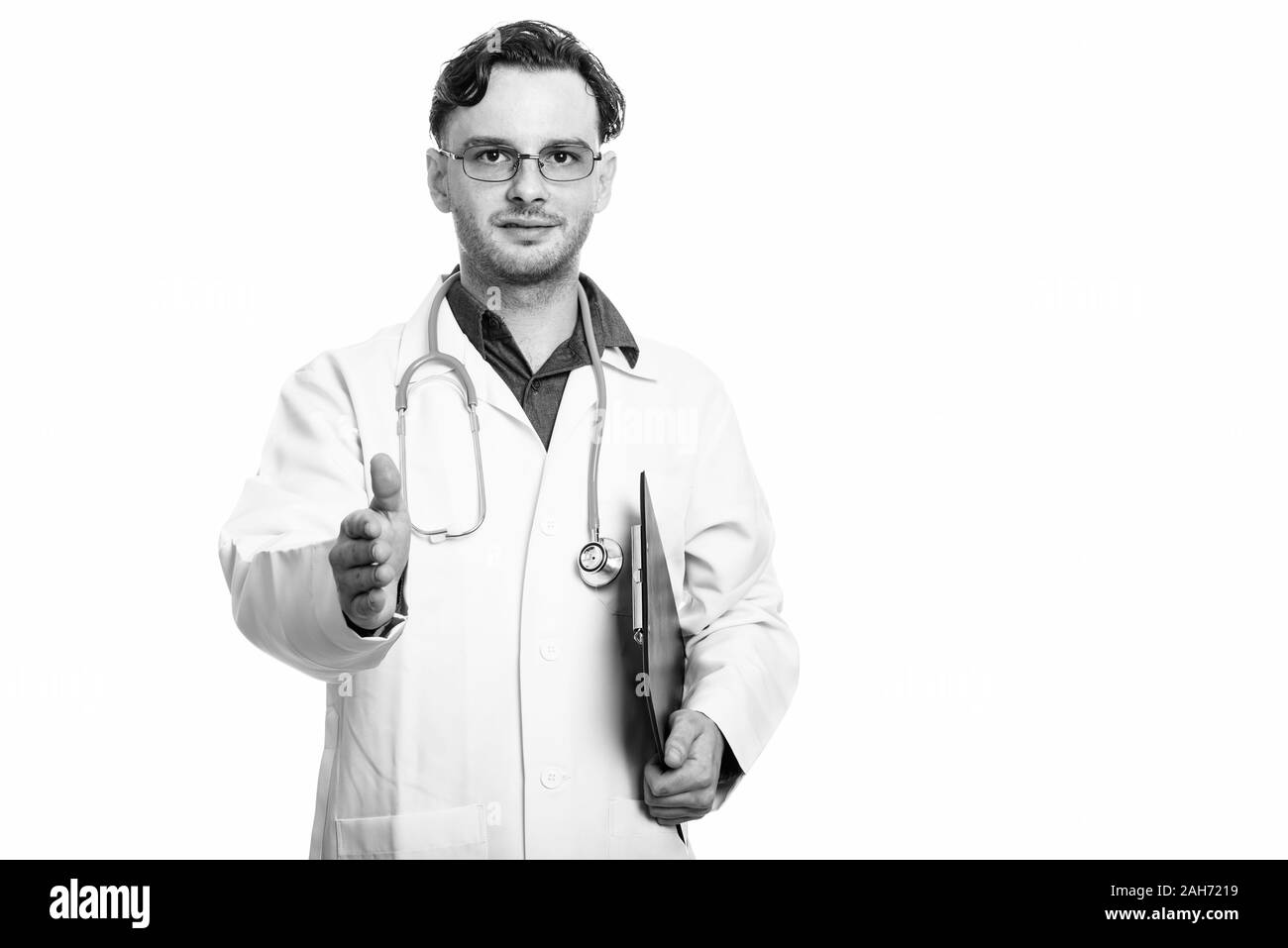 Studio erschossen der junge Mann Arzt holding Zwischenablage und Handshake Stockfoto