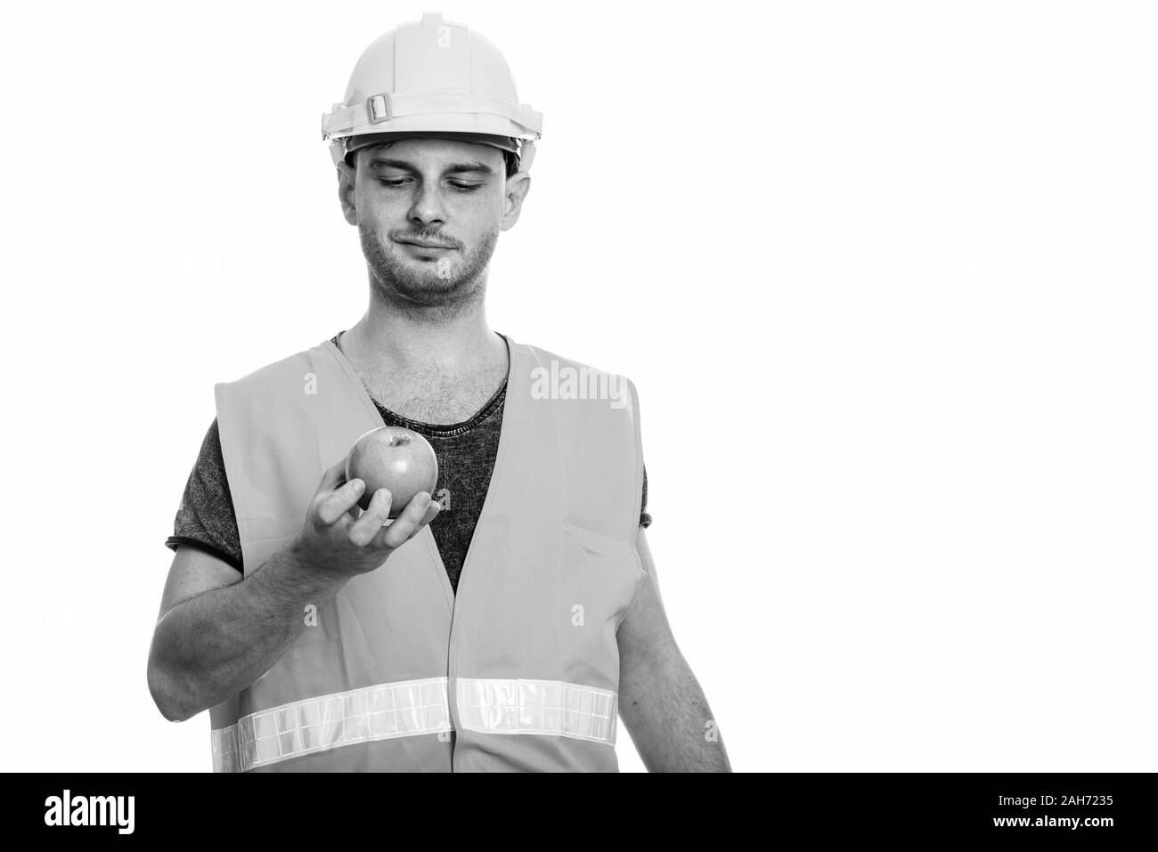 Studio shot des jungen Mannes Bauarbeiter Holding und im Green Apple suchen Stockfoto