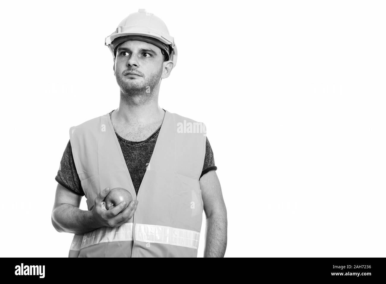 Studio shot des jungen Mannes Bauarbeiter Holding green apple beim Denken Stockfoto