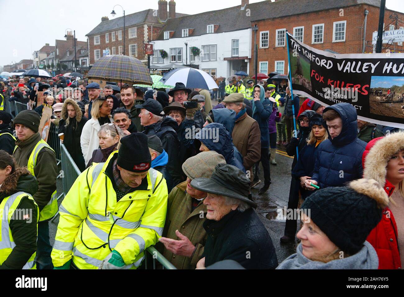 Tenterden, Kent, Großbritannien. 26. Dezember, 2019. Die jährlichen Boxing Day treffen der Ashford Tal Tickham Jagd findet im Zentrum von Tenterden in Kent. Hunde und Pferde versammeln sich in der 'Vine Inn Pub bei 11, bevor Sie die High Street zu einem verpackten Publikum bin. Das Wetter ist nass und regnerisch Regen. Fuchsjagd Demonstranten jeer die Fuchsjagd, wie sie weg. © Paul Lawrenson 2019, Foto: Paul Lawrenson/Alamy leben Nachrichten Stockfoto