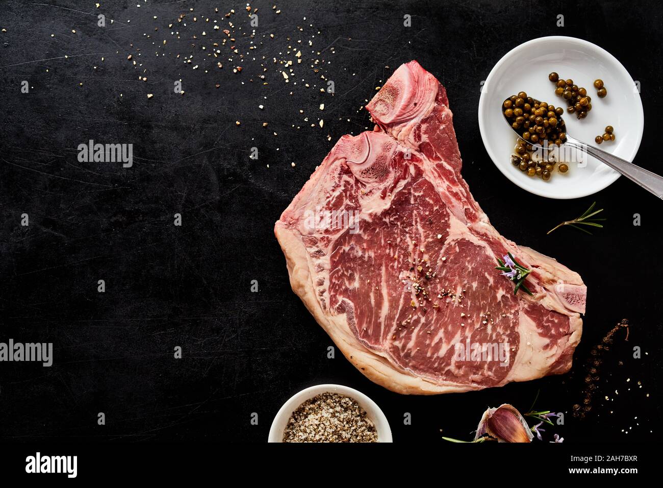 Raw marmoriert Cowboy Steak mit Gewürzen Zutaten auf einem dunklen Hintergrund mit Kopie Raum in einer Ansicht von oben Stockfoto