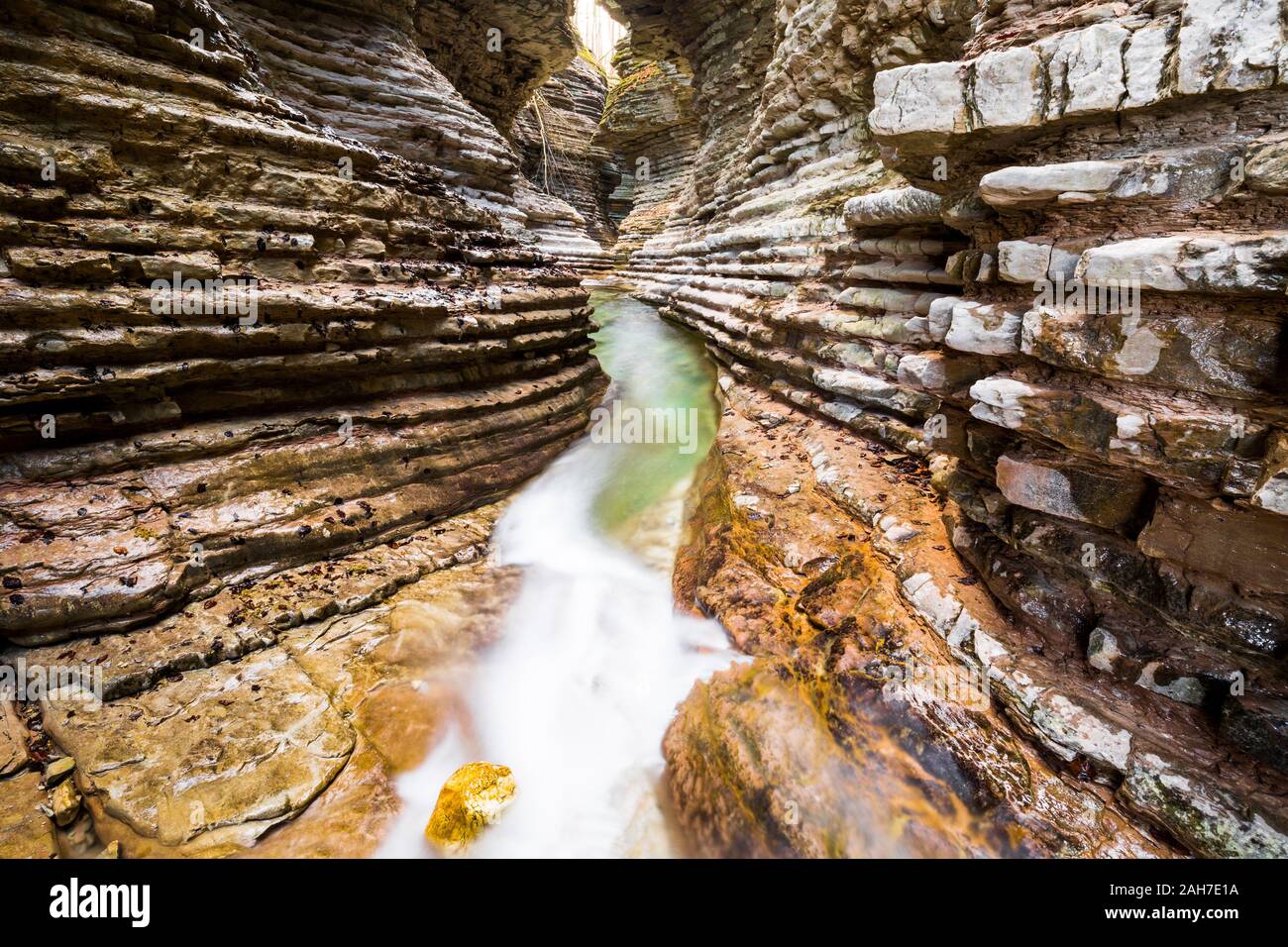 Symmetrische Weitwinkelansicht eines stratifizierten roten Sandsteinschluchtes mit einem Bach, der auf seinem Grund fließt Stockfoto