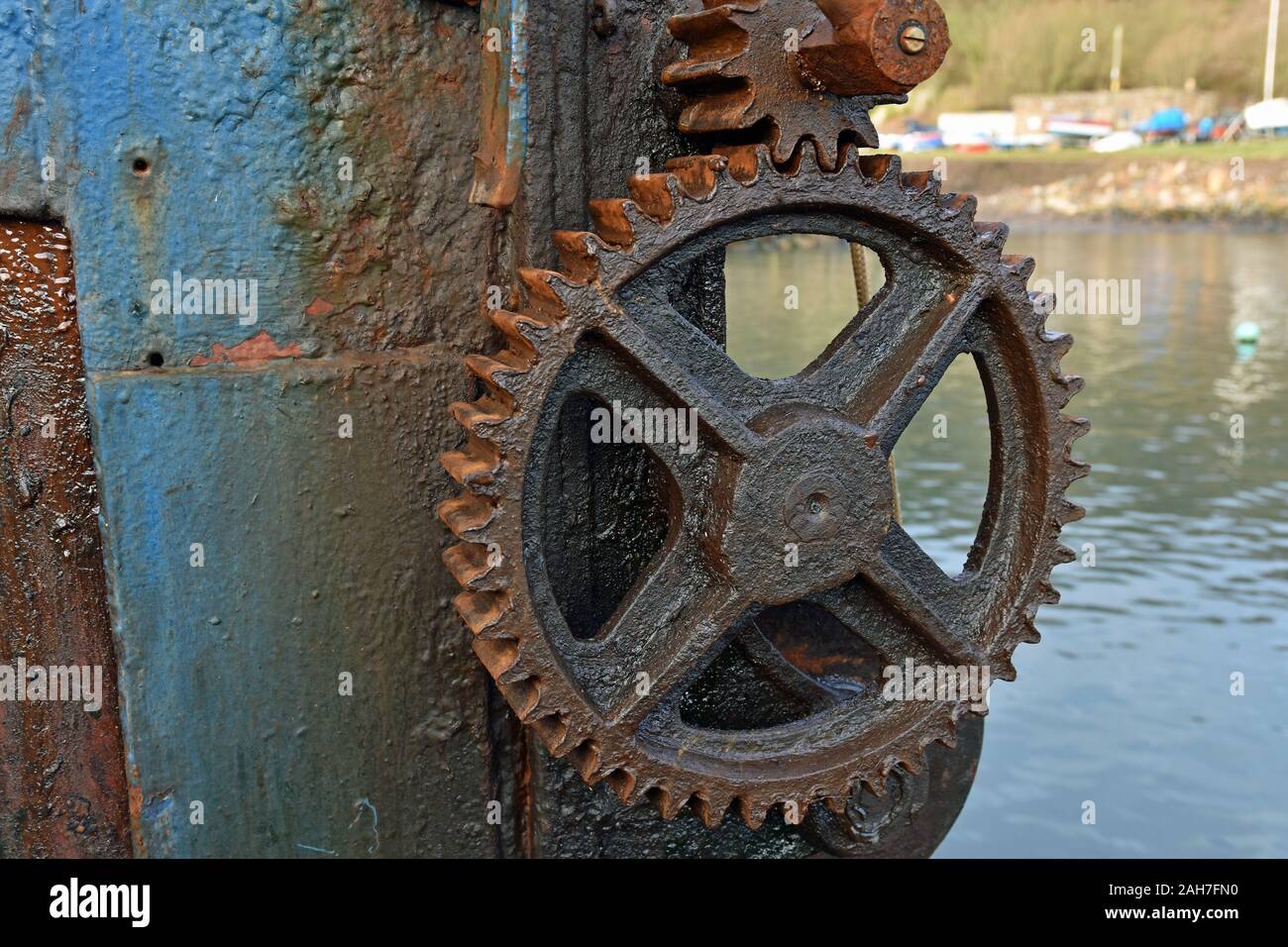 In der Nähe der alten manuellen Boot Anheben der Maschine im Hafen, mit verrosteten Rad- und Zahnradbahn mit Wasser und Boote unscharf im Hintergrund Stockfoto