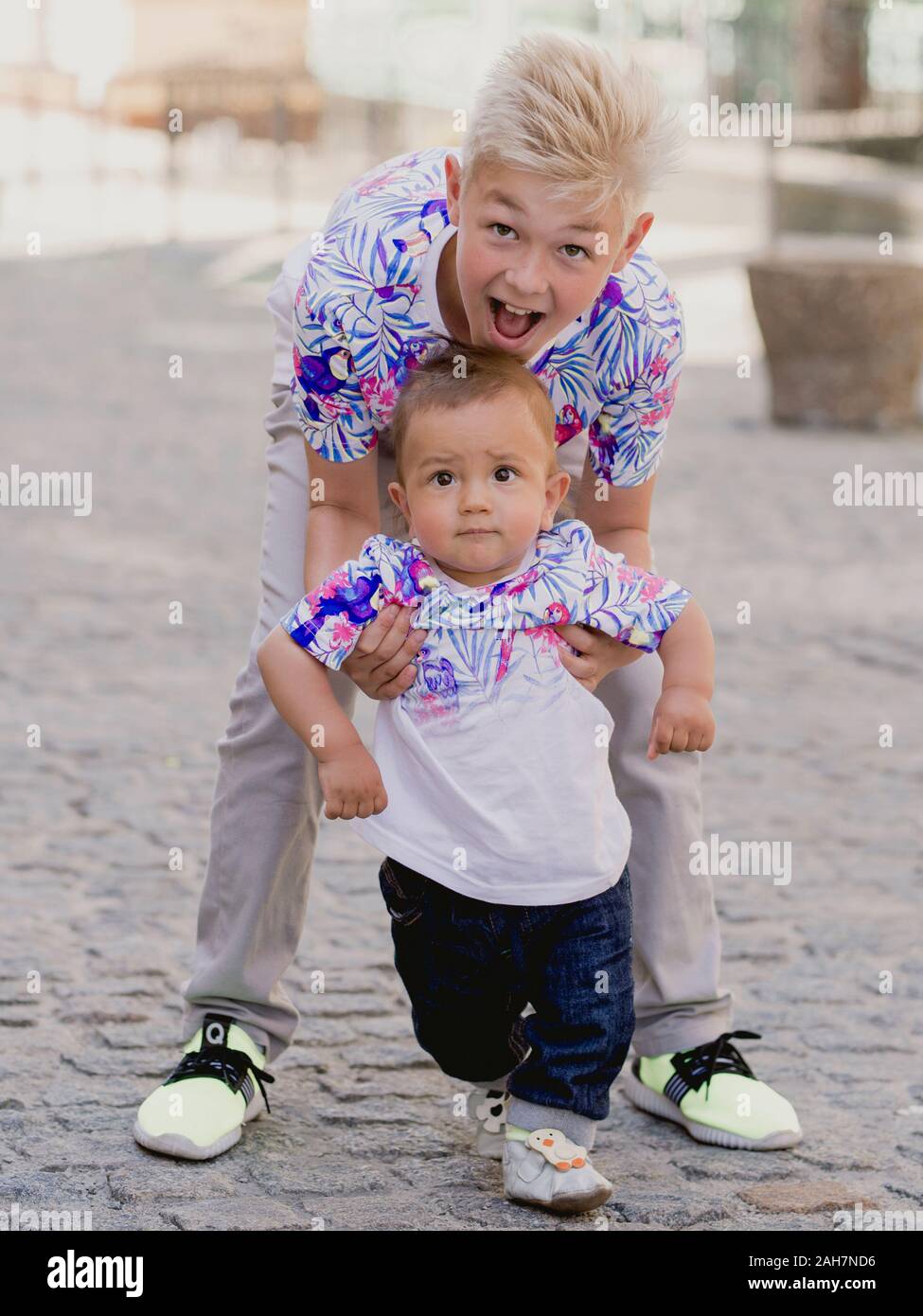 Kaukasische adorable süße Jungs Geschwister - ein helhing einen ersten Schritt zu machen. Familie, Hilfe, Support Konzept Stockfoto