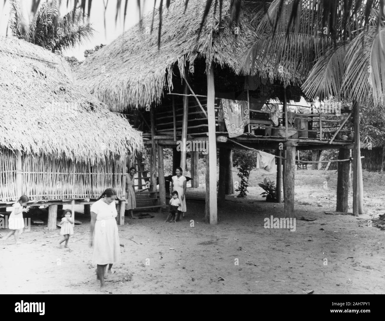British Guyana, einem indianischen Dorf in Britischen GuianaAmerindian Frauen und Kinder im Freien unter dem Gestelzten, strohgedeckten Behausungen eines Guyanese Dorf entspannen. British Guiana (Guyana), 1965, 1965. 2005/010/1/13/87. Stockfoto