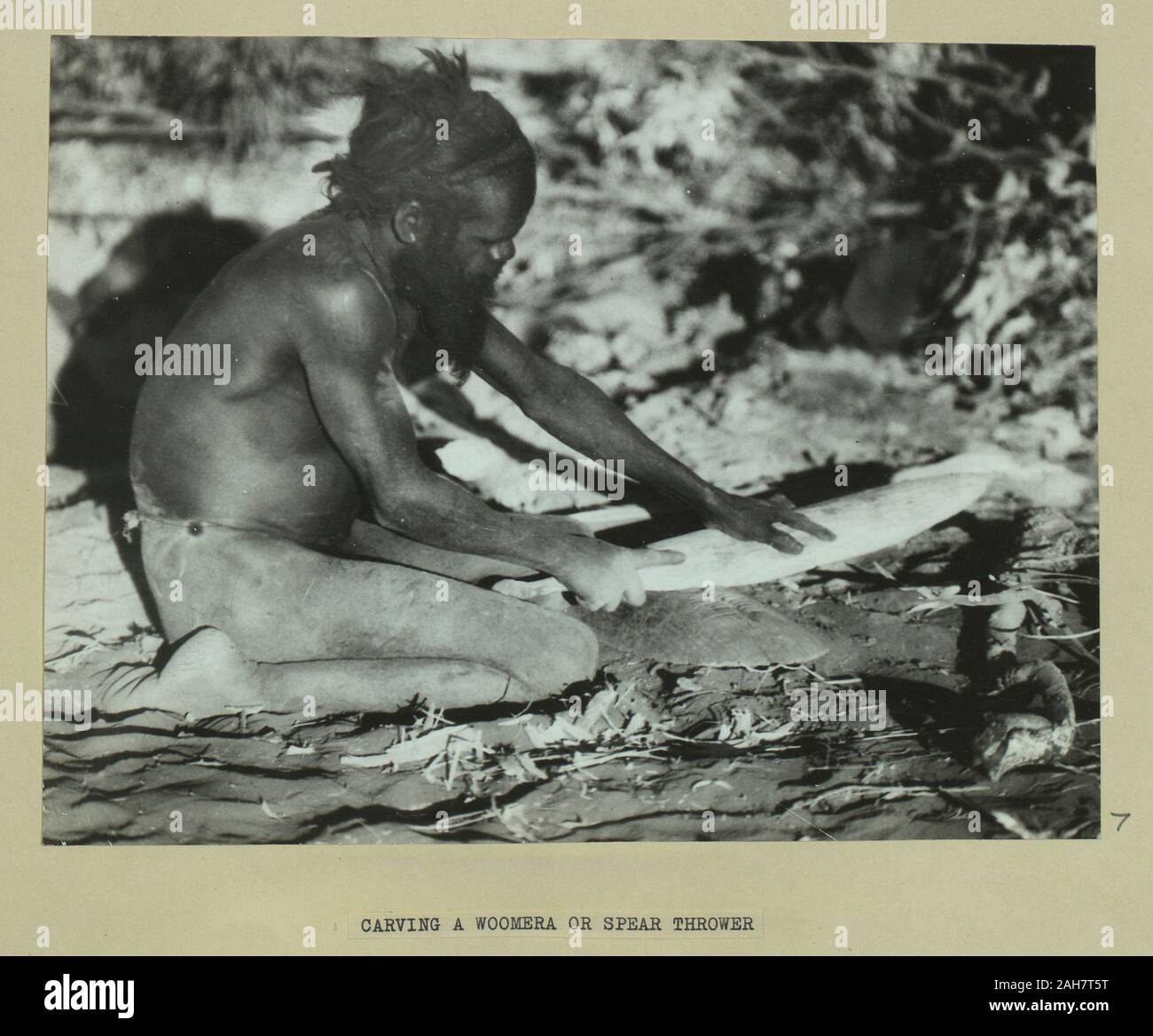 Australien, Aboriginal Mann Carving ein woomera oder Speerschleuder.Caption lautet: Carving ein woomera oder speerschleuder, 1925. 2005/010/1/2/7. Stockfoto