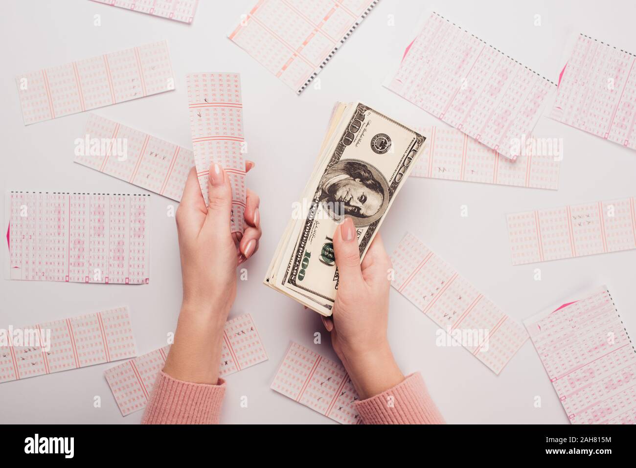 7/8-Ansicht von Frau mit Dollar Banknoten und Lottery Ticket in der Nähe verstreut Lotterie Karten auf weißen Tisch Stockfoto