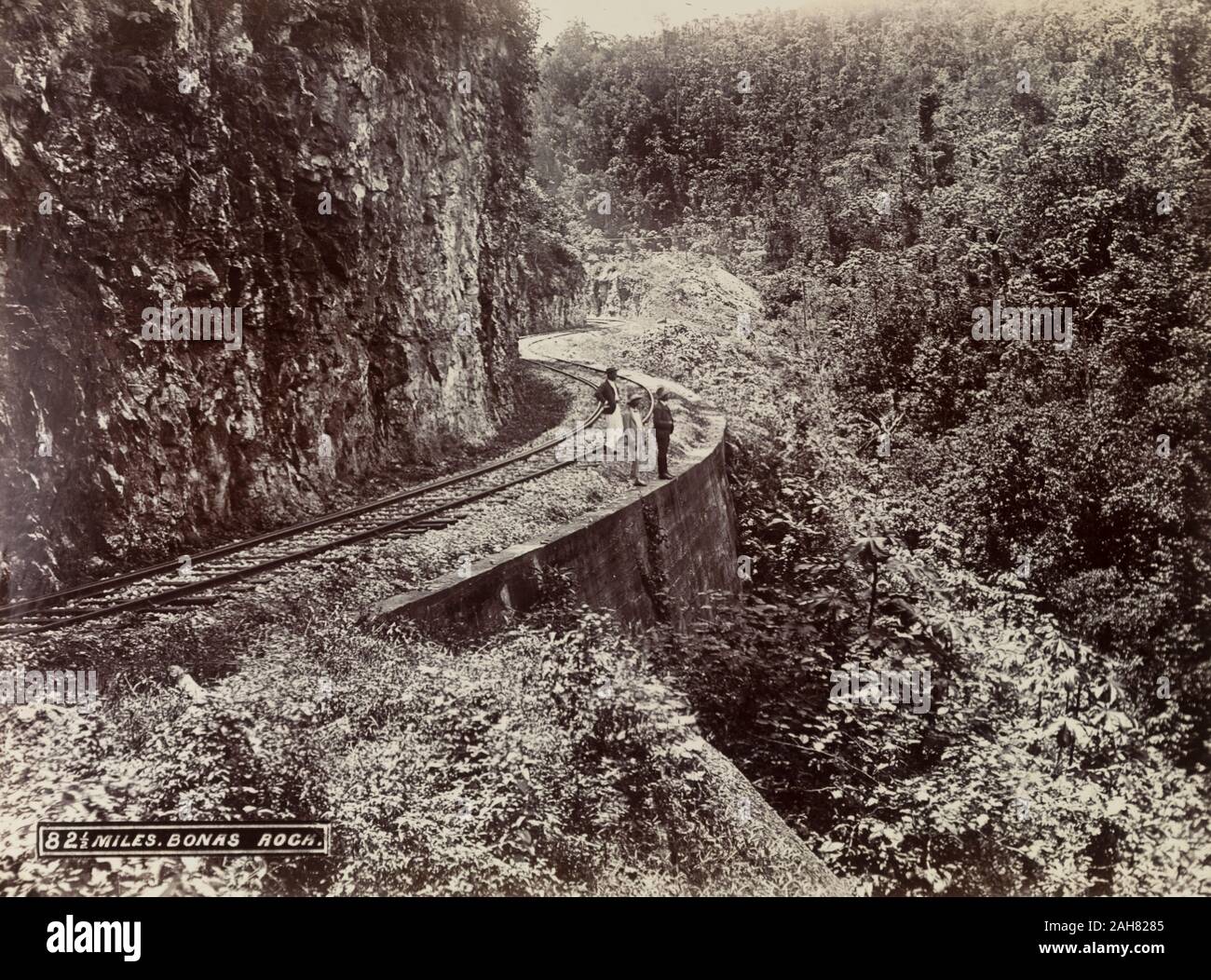 Jamaika, drei Männer stehen auf einer Strecke von der Bahnlinie, klammert sich an der Seite eines bewachsenen Berg an Bonas Rock, der sich auf eine Verlängerung der Laufzeit von Poros und Montego Bay.Caption im negativen liest: 82½ Meilen. Bonas Rock, 1894-1895. 1999/221/1/62/7. Stockfoto