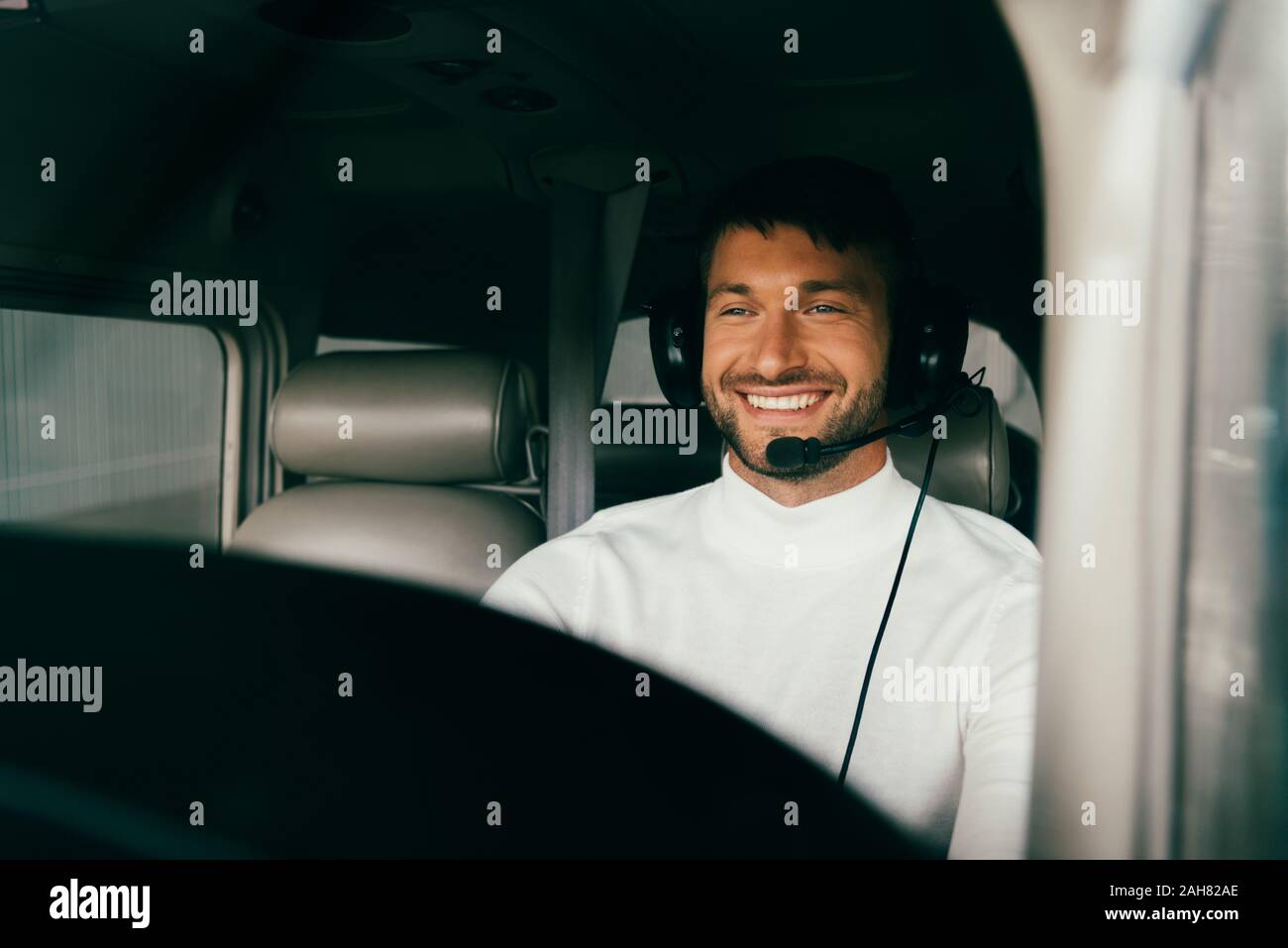 Lächelnd schöne bärtige pilot Headset in der Ebene Stockfoto