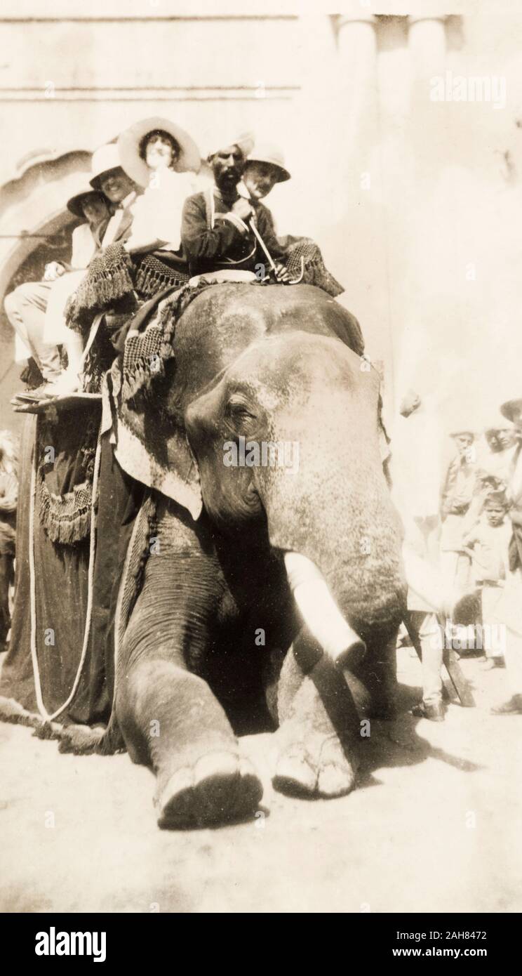 PakistanIndia, einer Gruppe von lächelnden Europäer sitzen in einem howdah auf dem Rücken eines Elefanten, während Sie für eine Fahrt vor. Der Elefant Mahout sitzt auf seinen Schultern, ankusha in der Hand. Originalmanuskript Bildunterschrift: LAHORE 3/4/20, 3. April 1920. 2001/243/1/1/3/22. Stockfoto