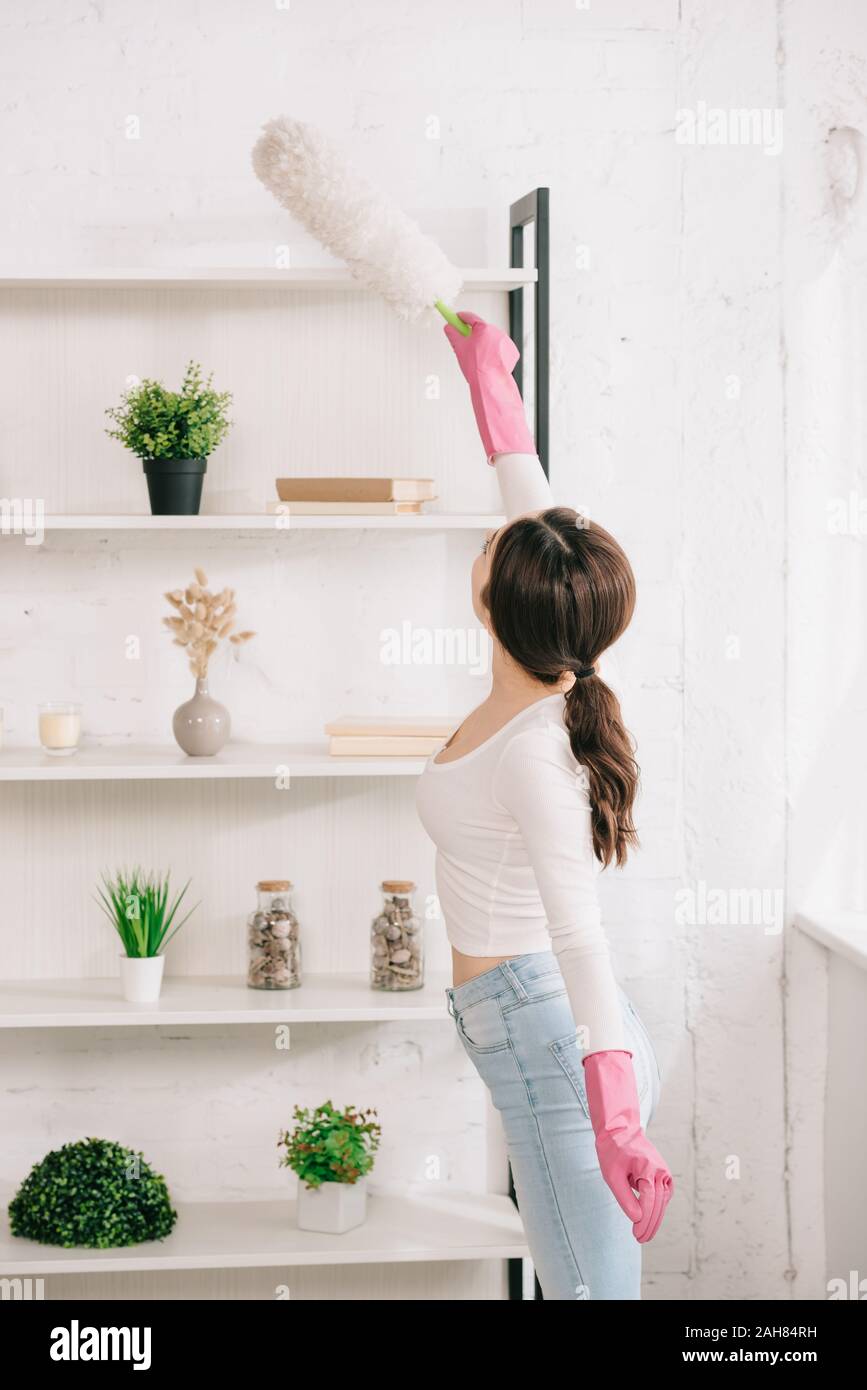 Junge Hausfrau Reinigung Rack mit weißen Staubbürste Stockfoto