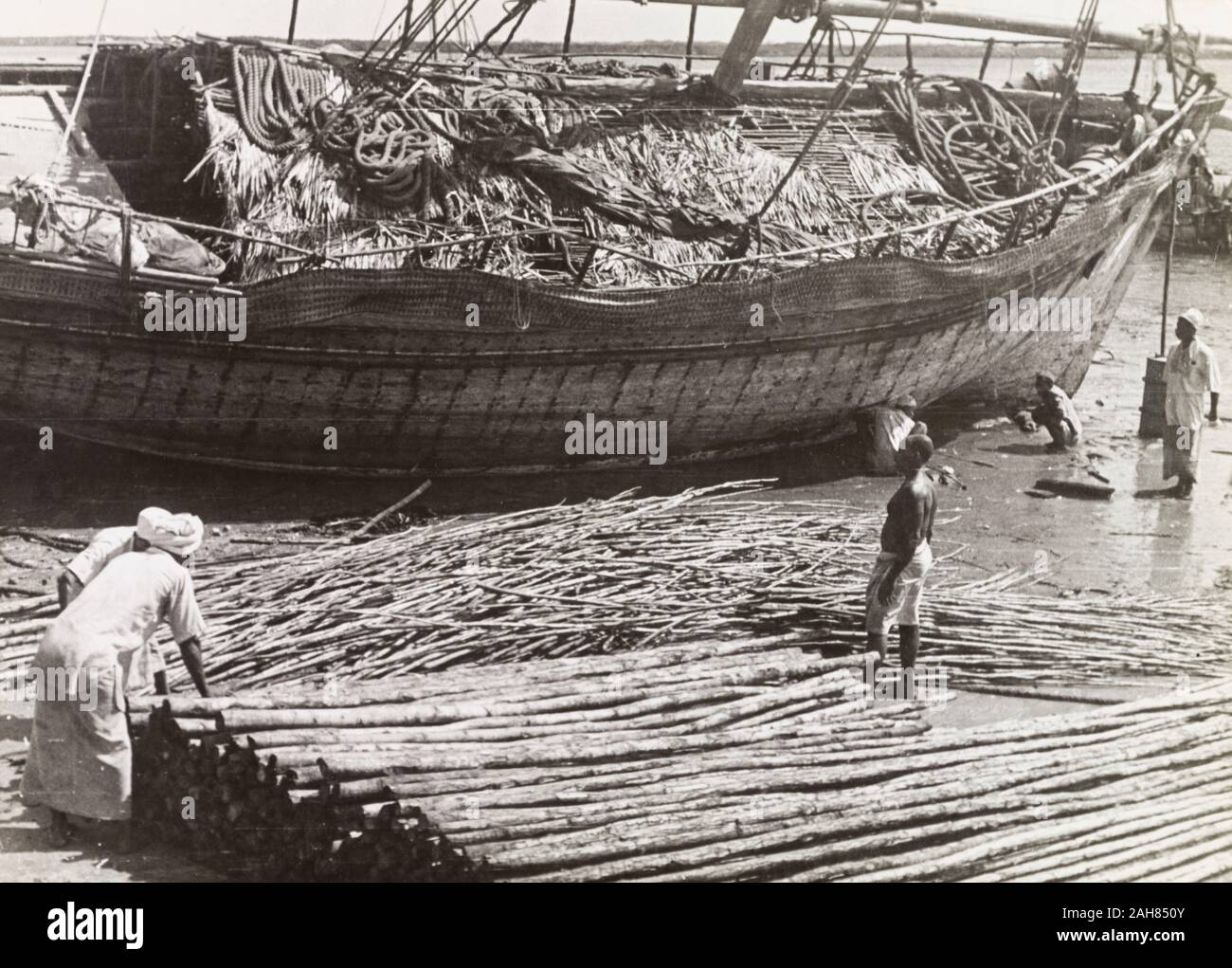 Kenia, Männer laden Mangroven Pole auf einem Dhau auf Lamu, bereit für den Export an den Persischen Golf. Originalmanuskript Bildunterschrift: Lamu - Laden Mangroven Pole, die Ausfuhr von der Insel, auf einem dhau, das sie an den Persischen Golf wenn der Monsun weht - ein Handel, der kaum für mindestens 1.000 Jahre, 1947 verändert hat. 1995/076/1/2/7/8. Stockfoto