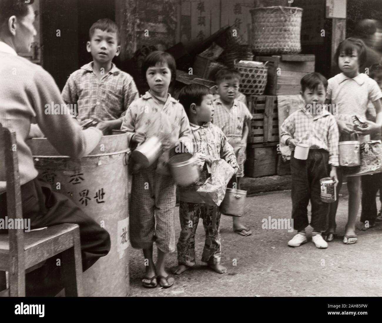 Hong Kong, Kinder Queuing für Lebensmittel, Hong KongCity Kinder queue mit tin-Container, warten Lebensmittelrationen von einer wohltätigen Organisation zu erhalten. Originalmanuskript Bildunterschrift: Kinder Queuing für eine Mahlzeit durch einige gemeinnützige Organisation, die 1963 zur Verfügung gestellt. 2005/010/1/11/40. Stockfoto