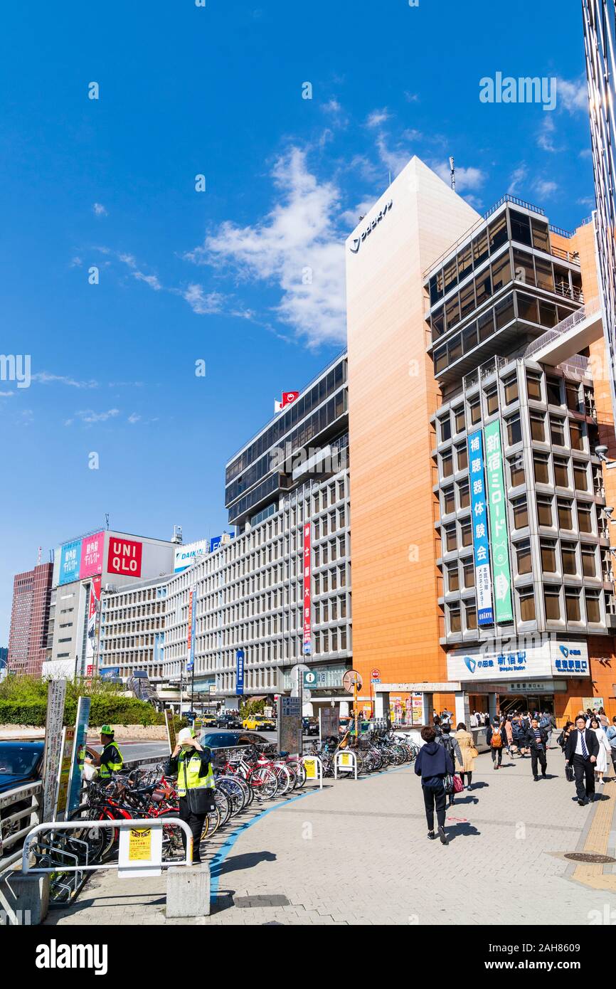 Tagsüber Blick entlang der Straßen mit dem Fahrrad Parkplatz, der Eingang West von Shinjuku und der Odakyu Department Store, Tokio. Blue Sky. Stockfoto