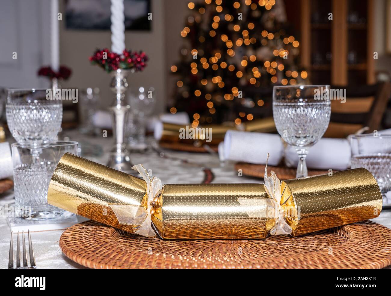 Traditionelle britische Weihnachtsessen Tabelle Einstellung mit Crackern und Gläser mit Xmas Tree im Hintergrund Stockfoto