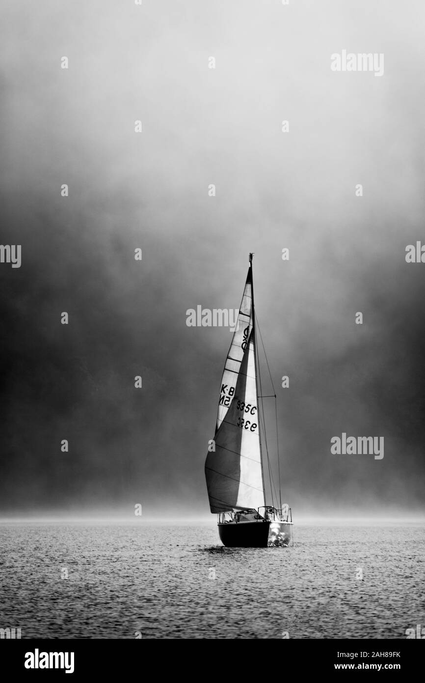 Freizeit Boot im Nebel auf einer frühen Herbst Morgen kurz nach Sonnenaufgang auf dem Coniston Water im Lake District, Cumbria, England. Stockfoto