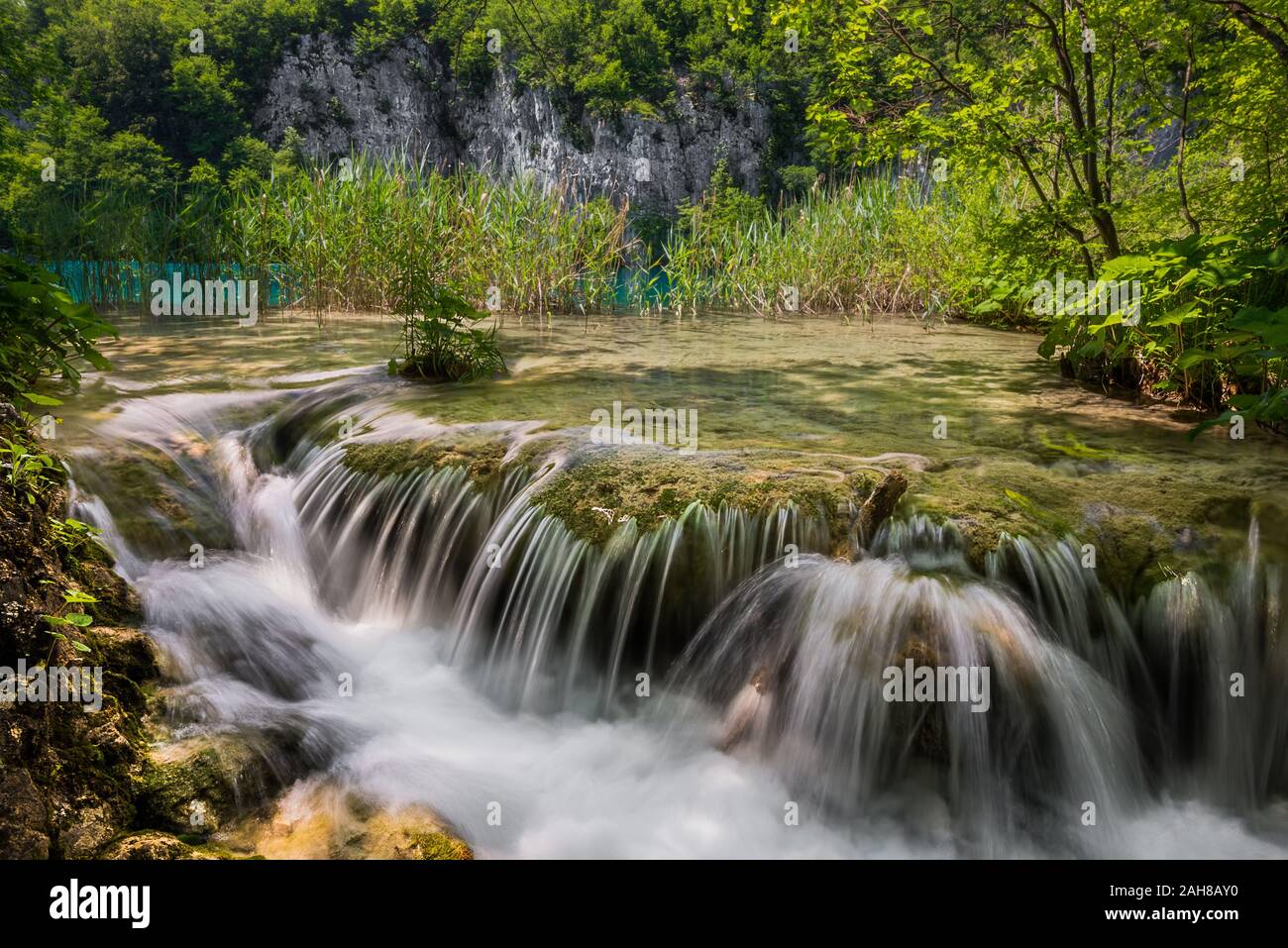 Weitwinkelansicht eines Baches, der in Stromschnellen fließt, umgeben von Vegetation im Plitvice Wasserfall Park Stockfoto