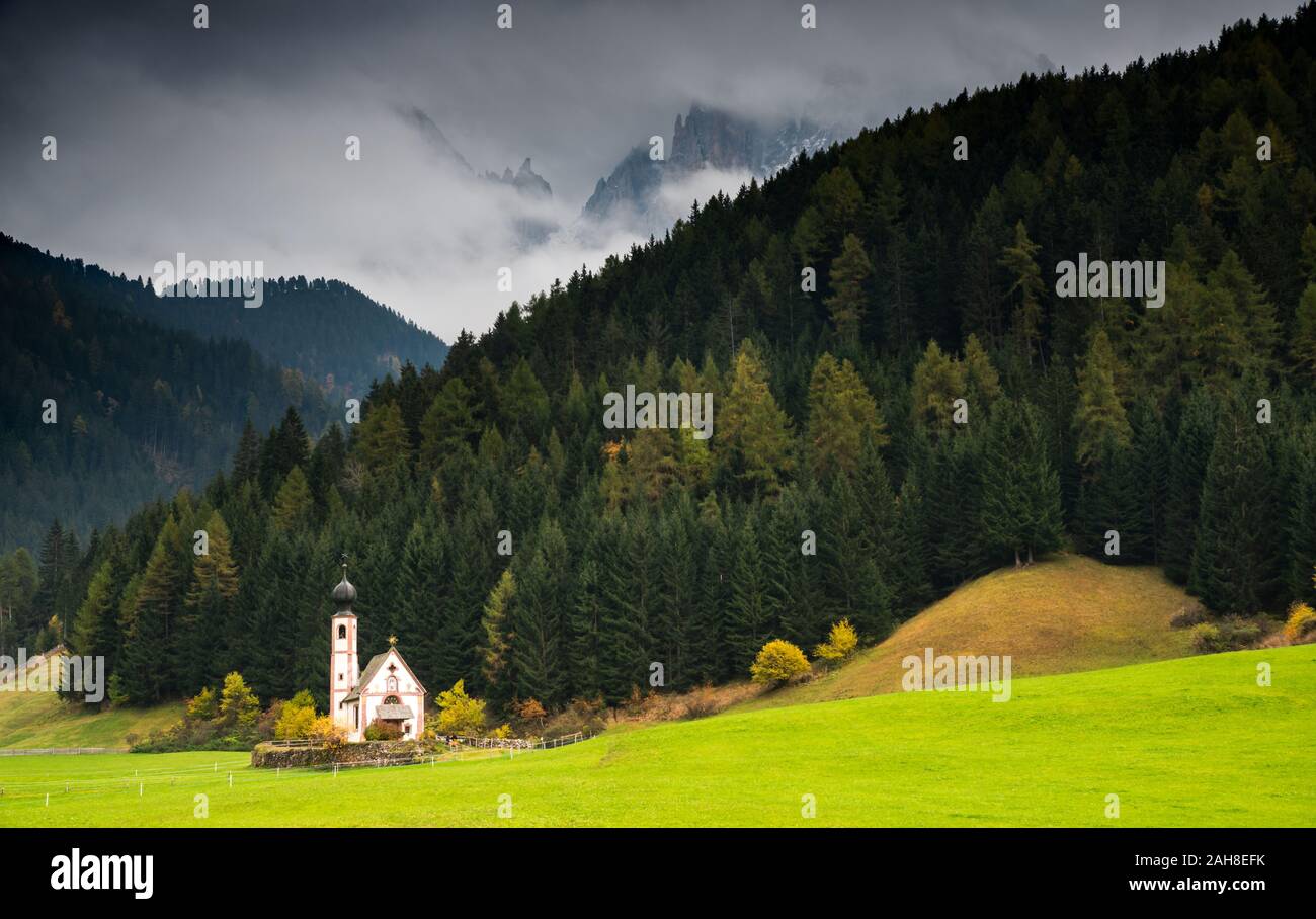 Die kleine und schöne Kirche des Heiligen Johannes, Ranui, chiesetta di San Giovanni in Ranui Runen Südtirol Italien, umgeben von grünen Wiesen, Wald ein Stockfoto