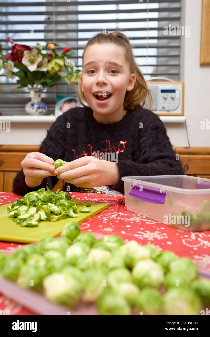 12 jährige Mädchen peeling Sprossen am Tisch, England Stockfoto