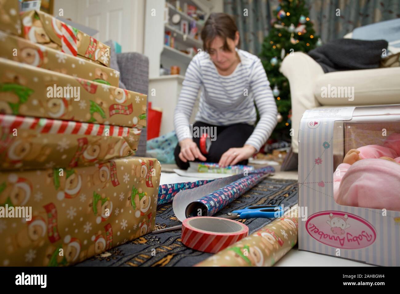 Junge Frau Verpackung Weihnachtsgeschenke auf dem Boden Stockfoto