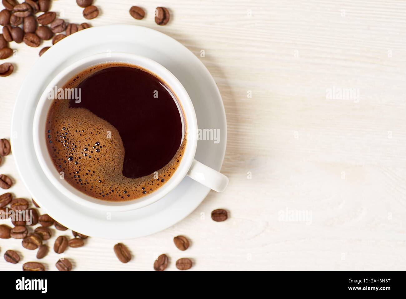 Americano und Kaffeebohnen auf weissem Holztisch Stockfoto