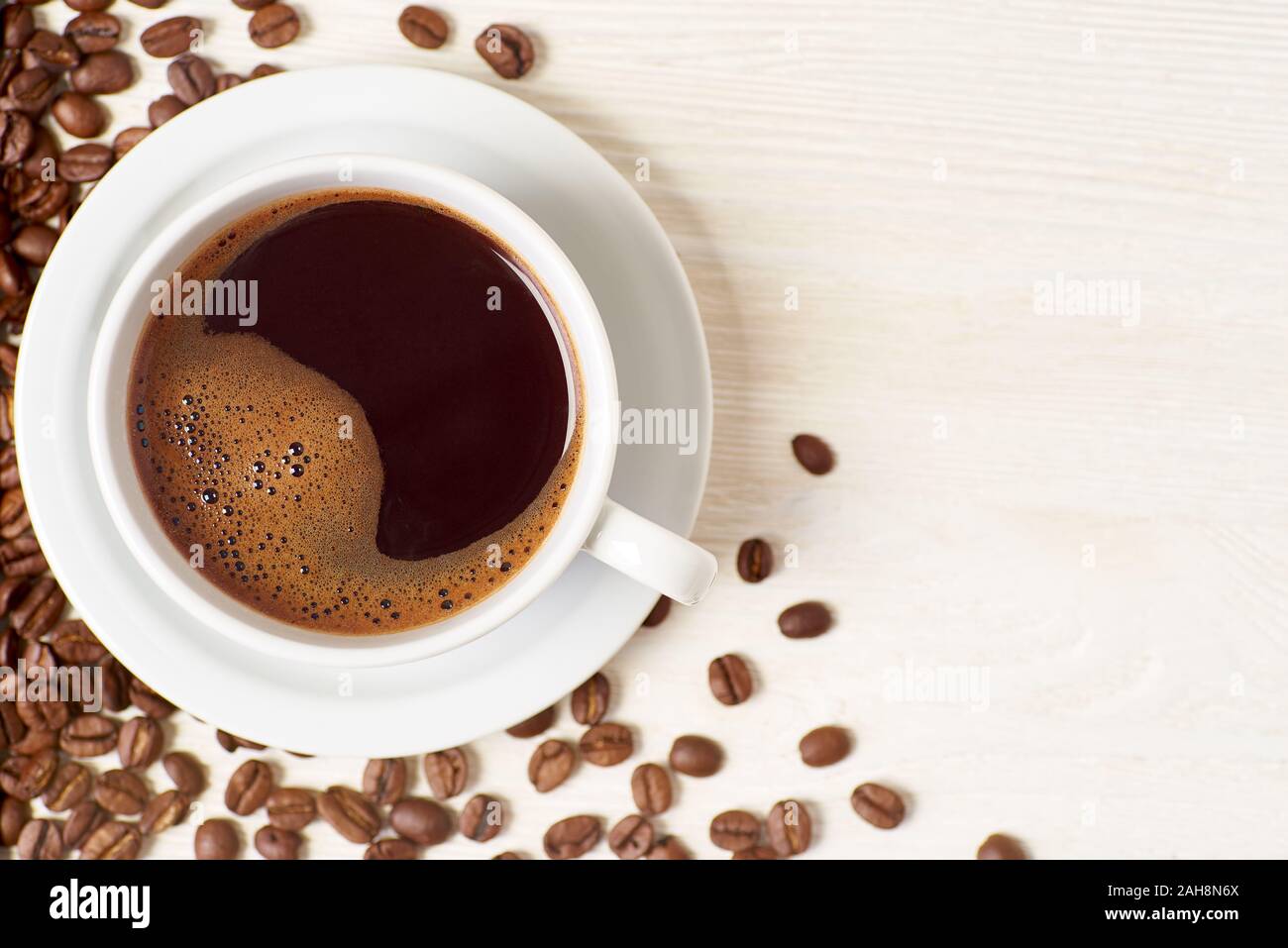 Americano und Kaffeebohnen auf weißem Holz- Hintergrund Stockfoto