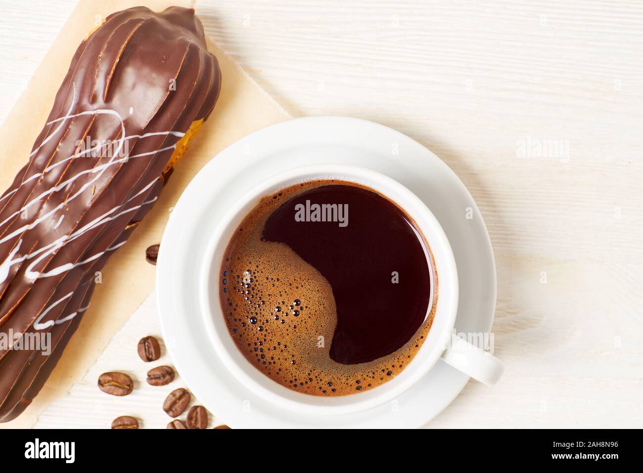 Eclair und Tasse Kaffee auf weiße Holztisch Stockfoto