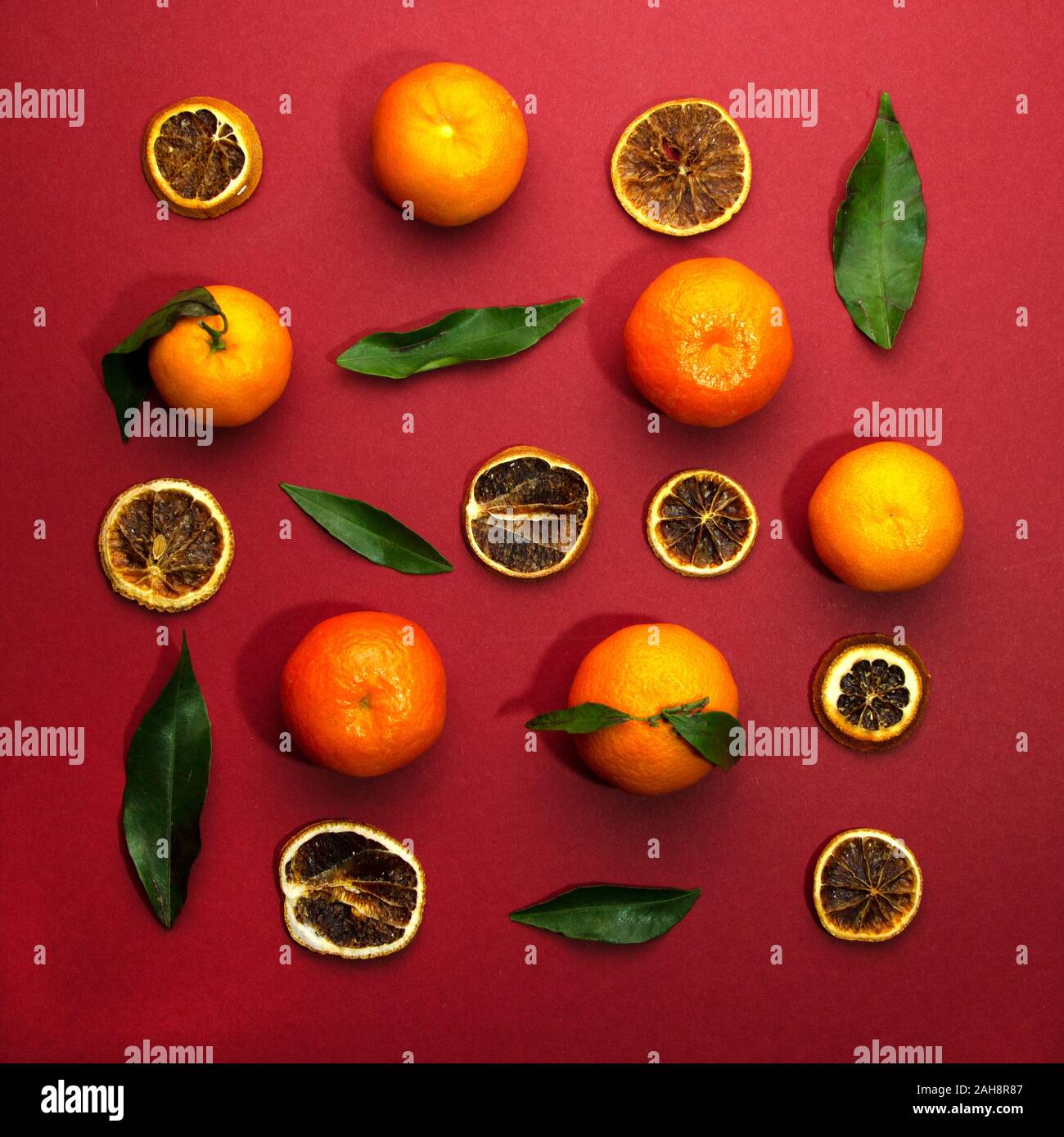 Frische Tangerinen und Scheiben getrocknete Orangen auf roten Hintergrund. Neues Jahr oder Weihnachtskarte. Stockfoto