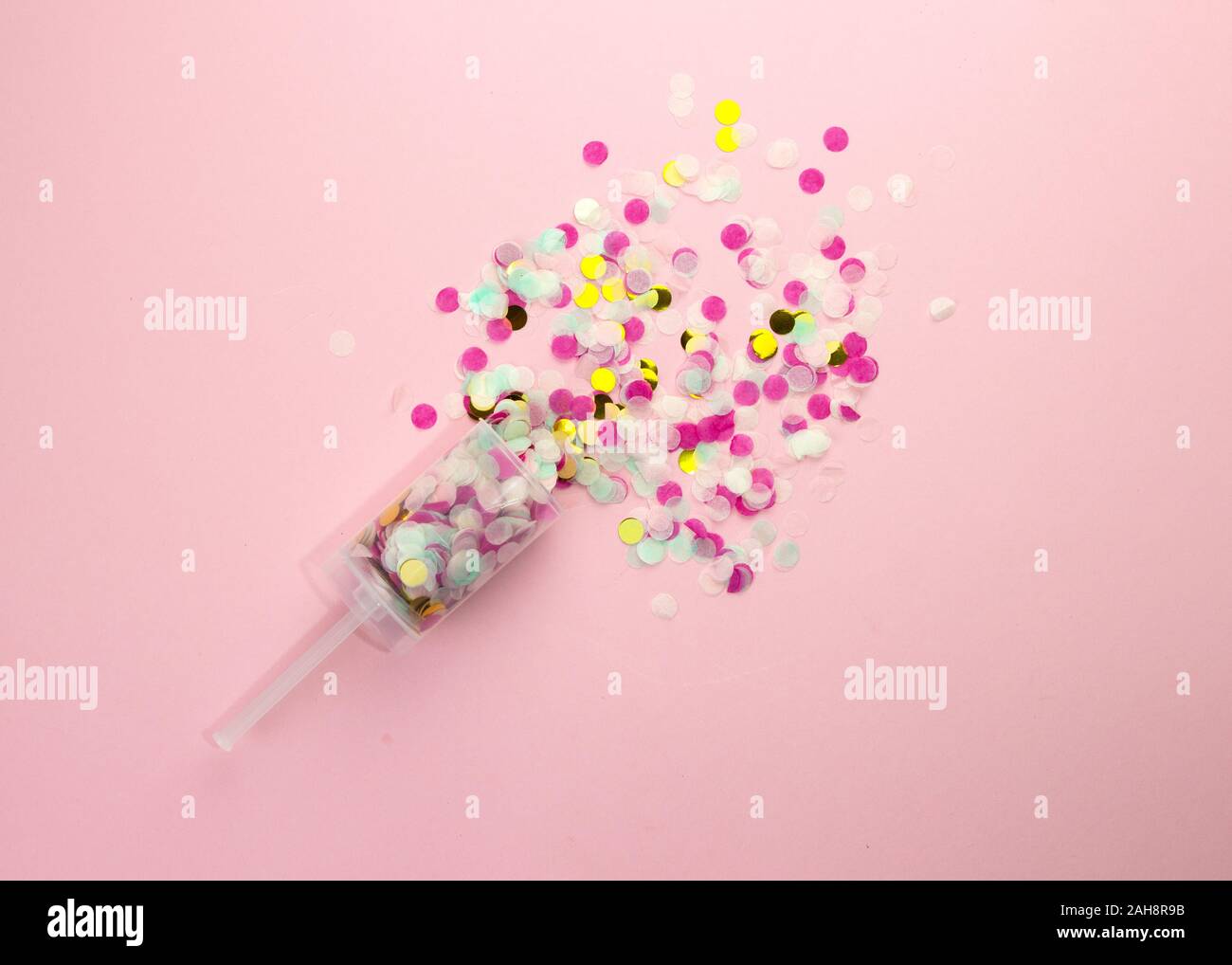 Popper mit bunten Papier Konfetti auf einem rosa Hintergrund. Stockfoto